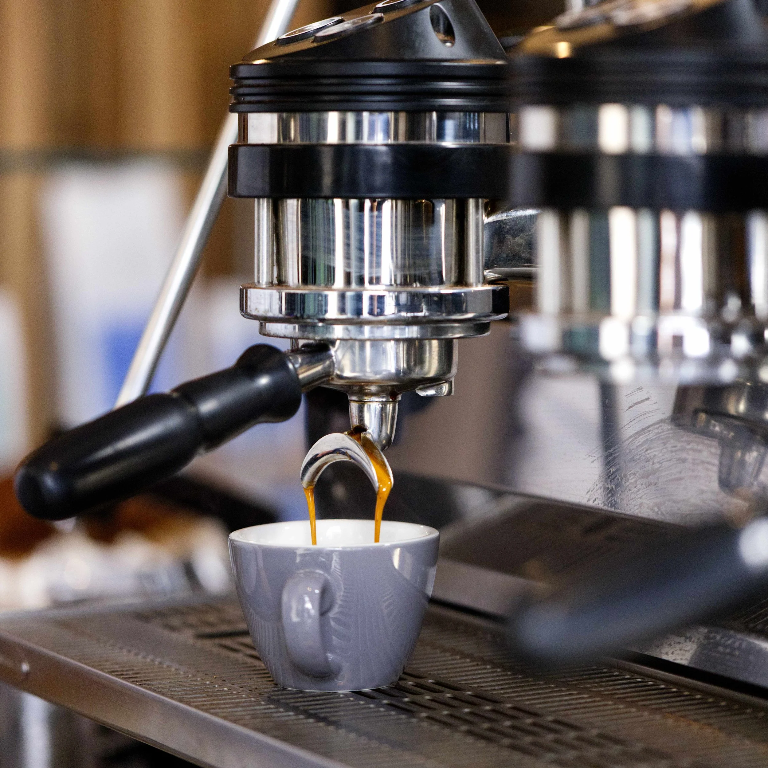 Close-up of an espresso machine brewing coffee into a gray mug.