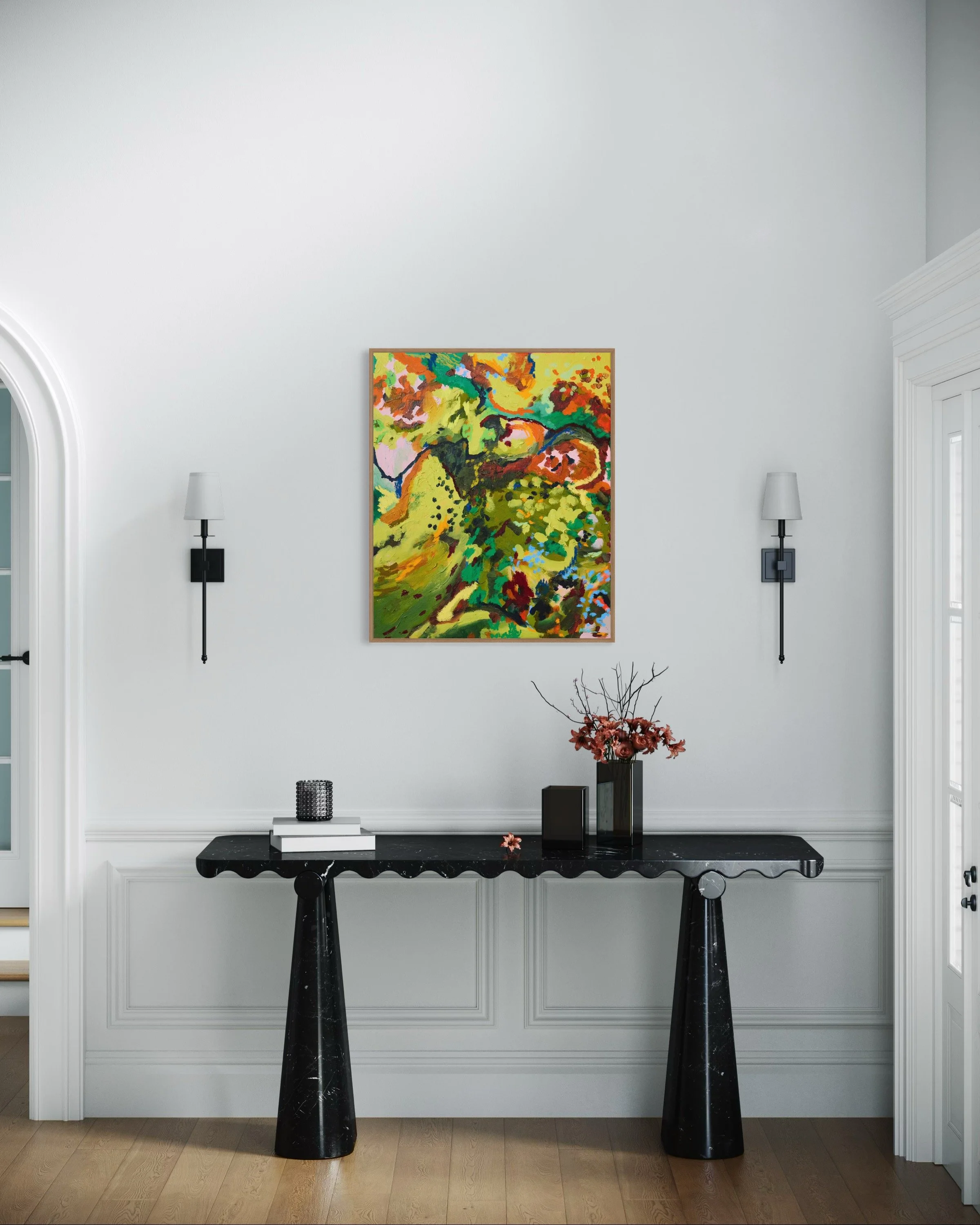 Modern interior hallway with a large abstract colorful painting on a white wall, decorated with two black wall sconces, a black console table holding a vase with flowers, books, and decorative objects, and hardwood flooring.