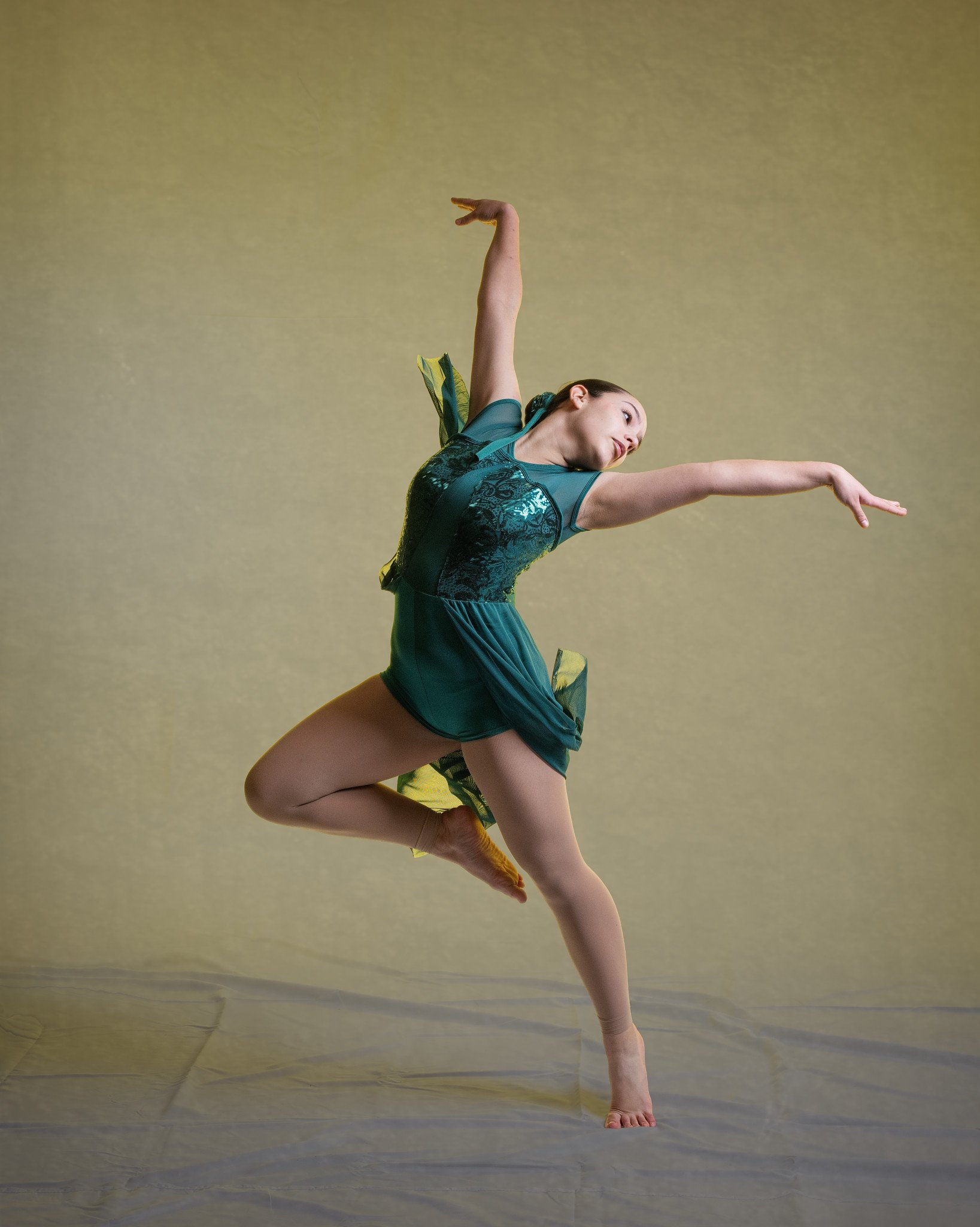 A female dancer in a green costume performing a dance move against a yellow background. Thetford dance photography at butterflies k-photography.
