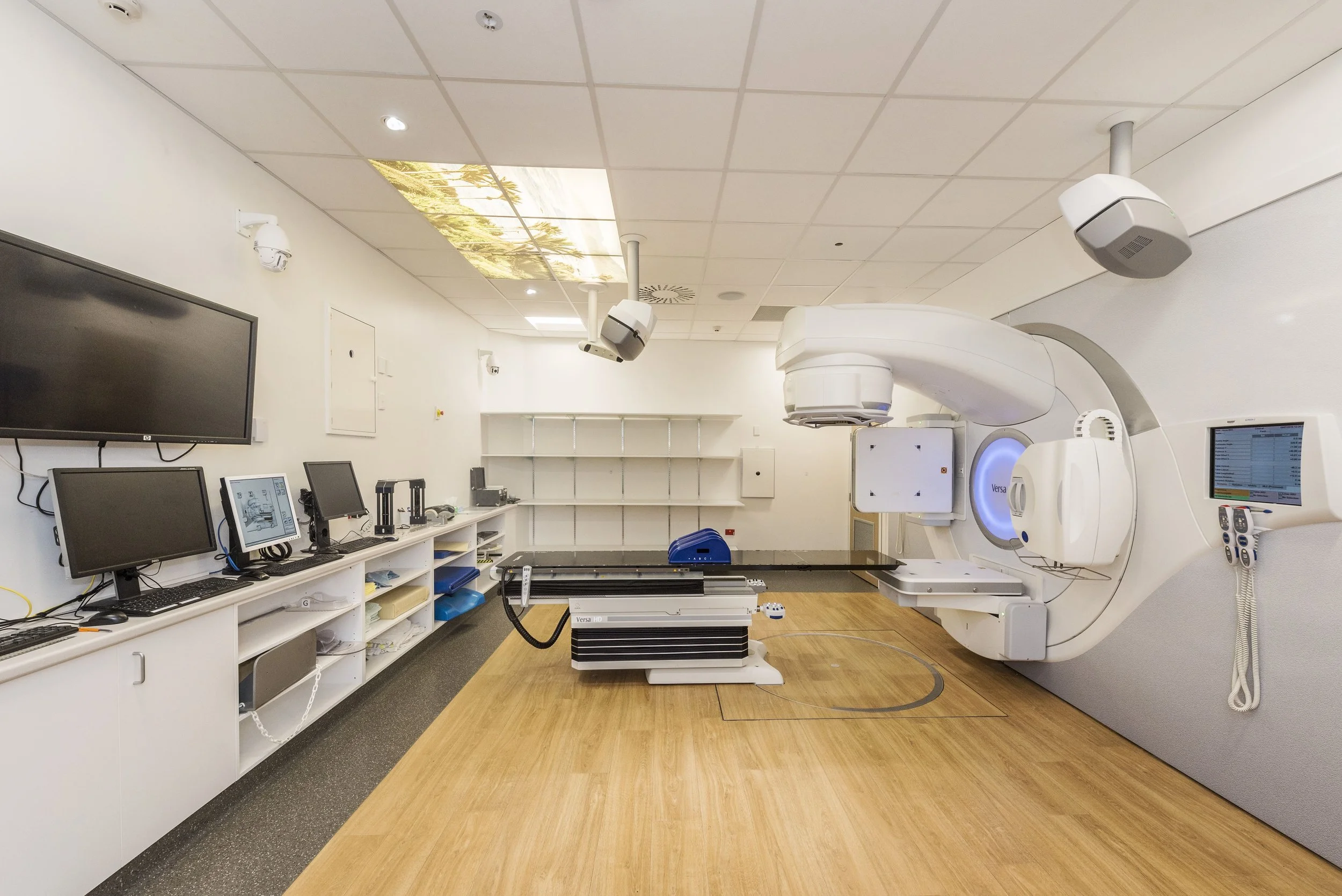 A medical imaging room with a large MRI machine, multiple computer monitors, and related equipment.