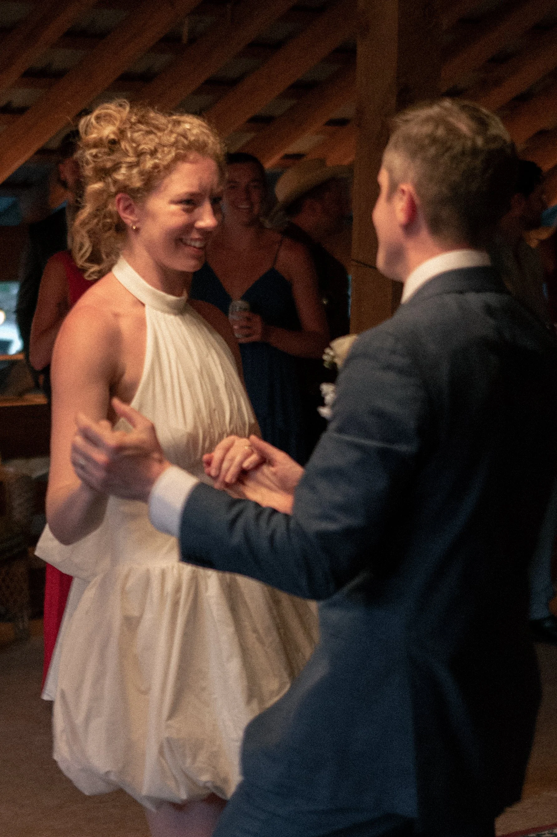 A woman in a white dress and man in a suit dancing at a wedding reception.