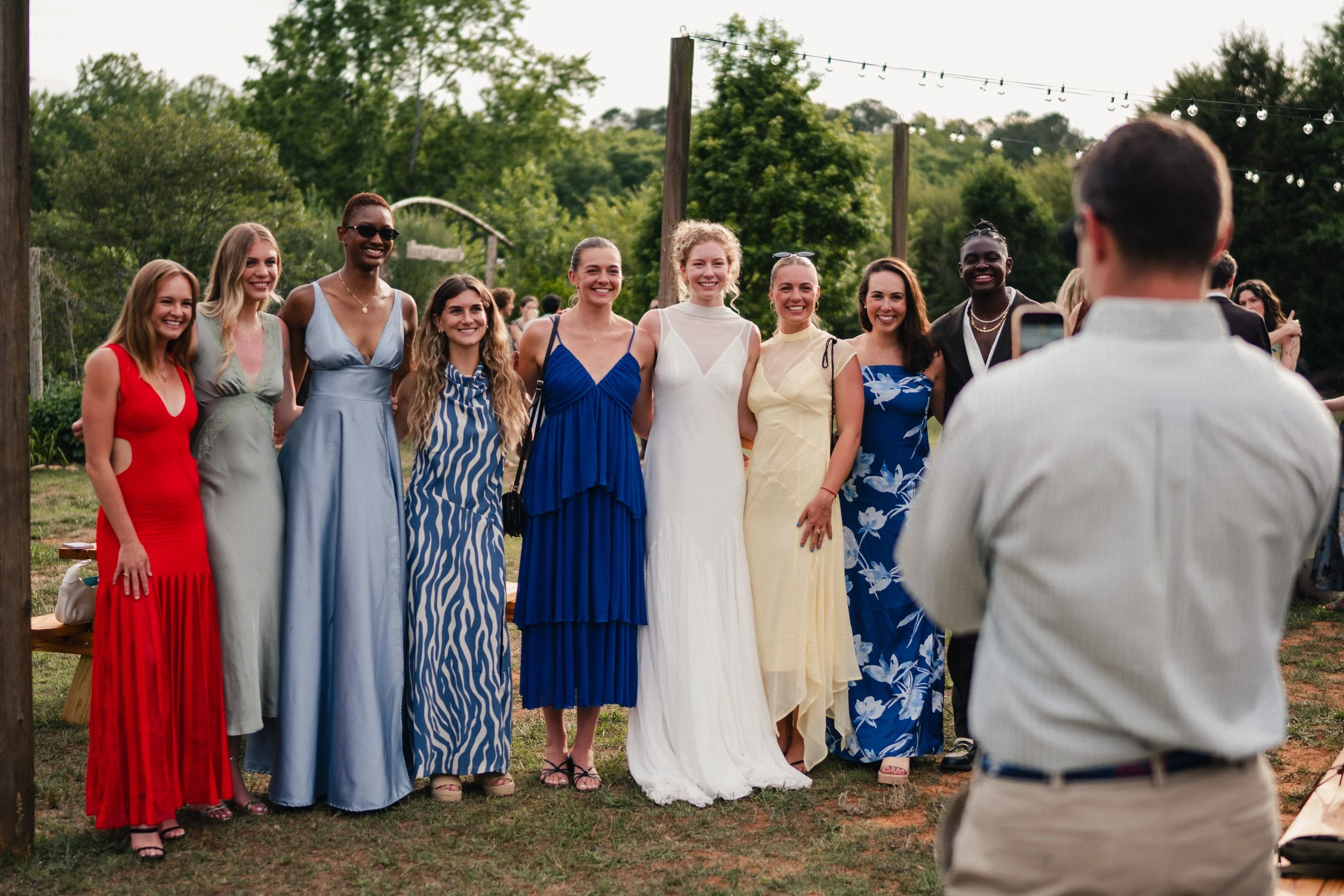 Group of women in colorful dresses posing for a photo at an outdoor event.