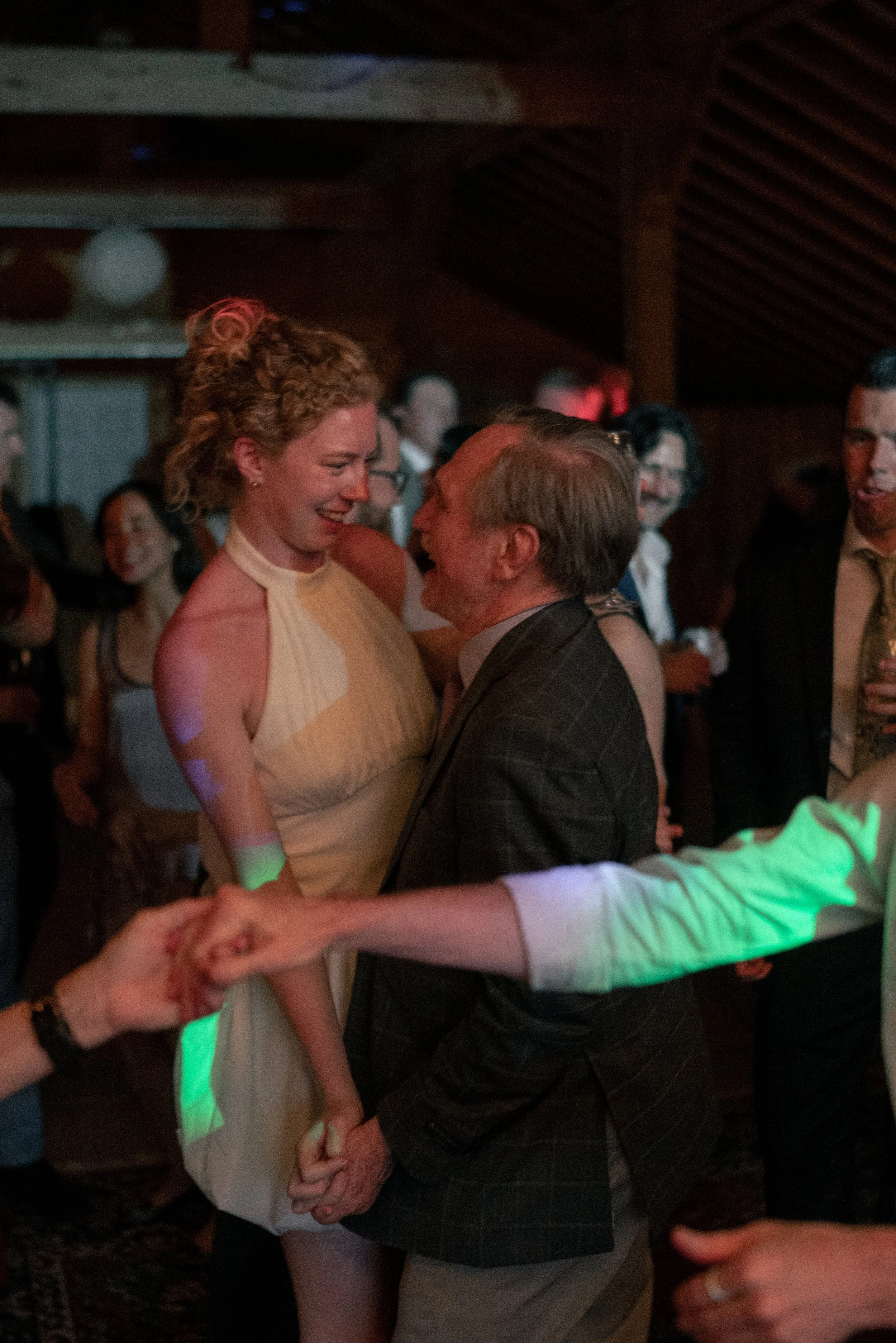 Couple dancing at a party with others in the background, people smiling and enjoying themselves.