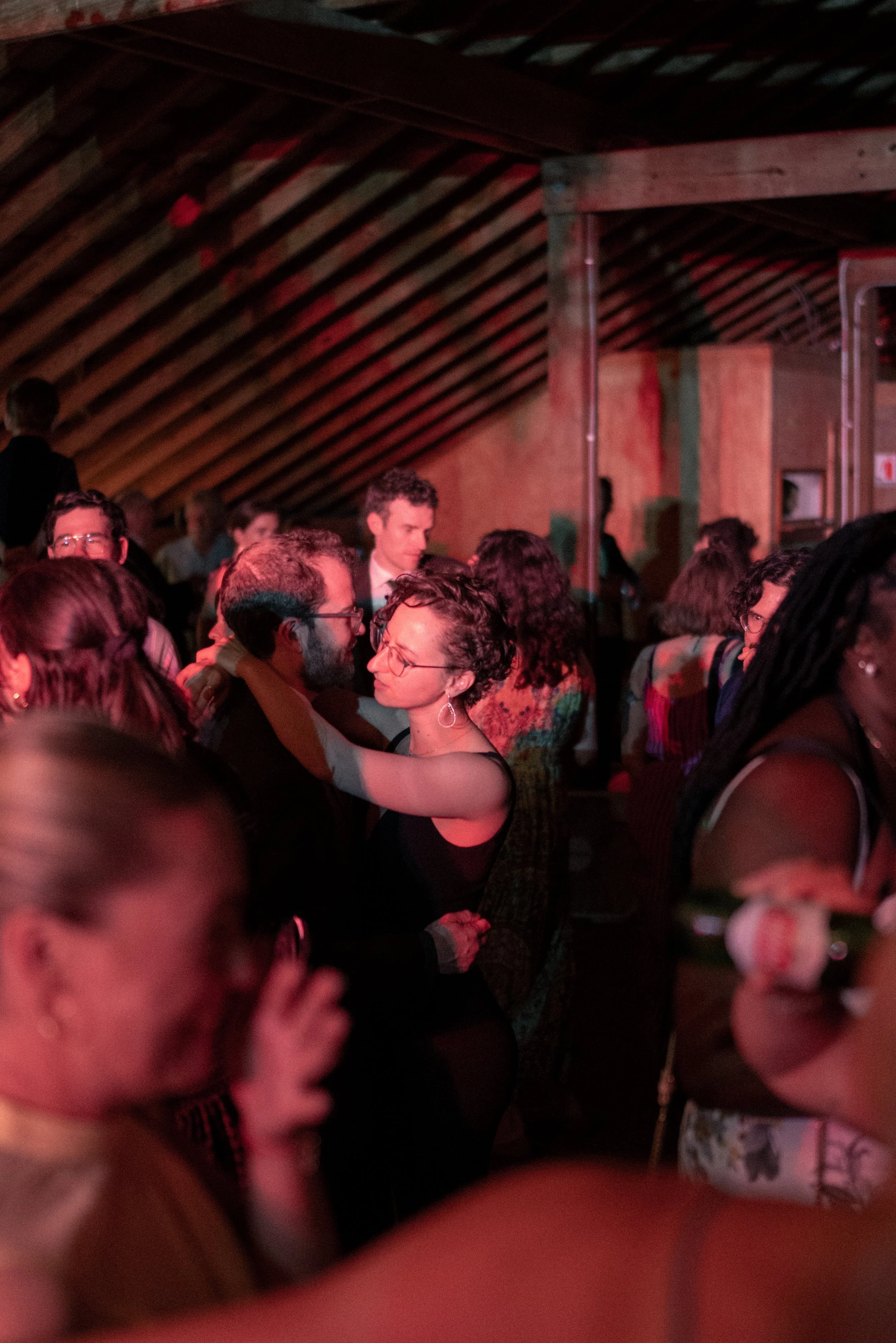 People dancing closely together in a dimly lit indoor setting, possibly at a social gathering or party.