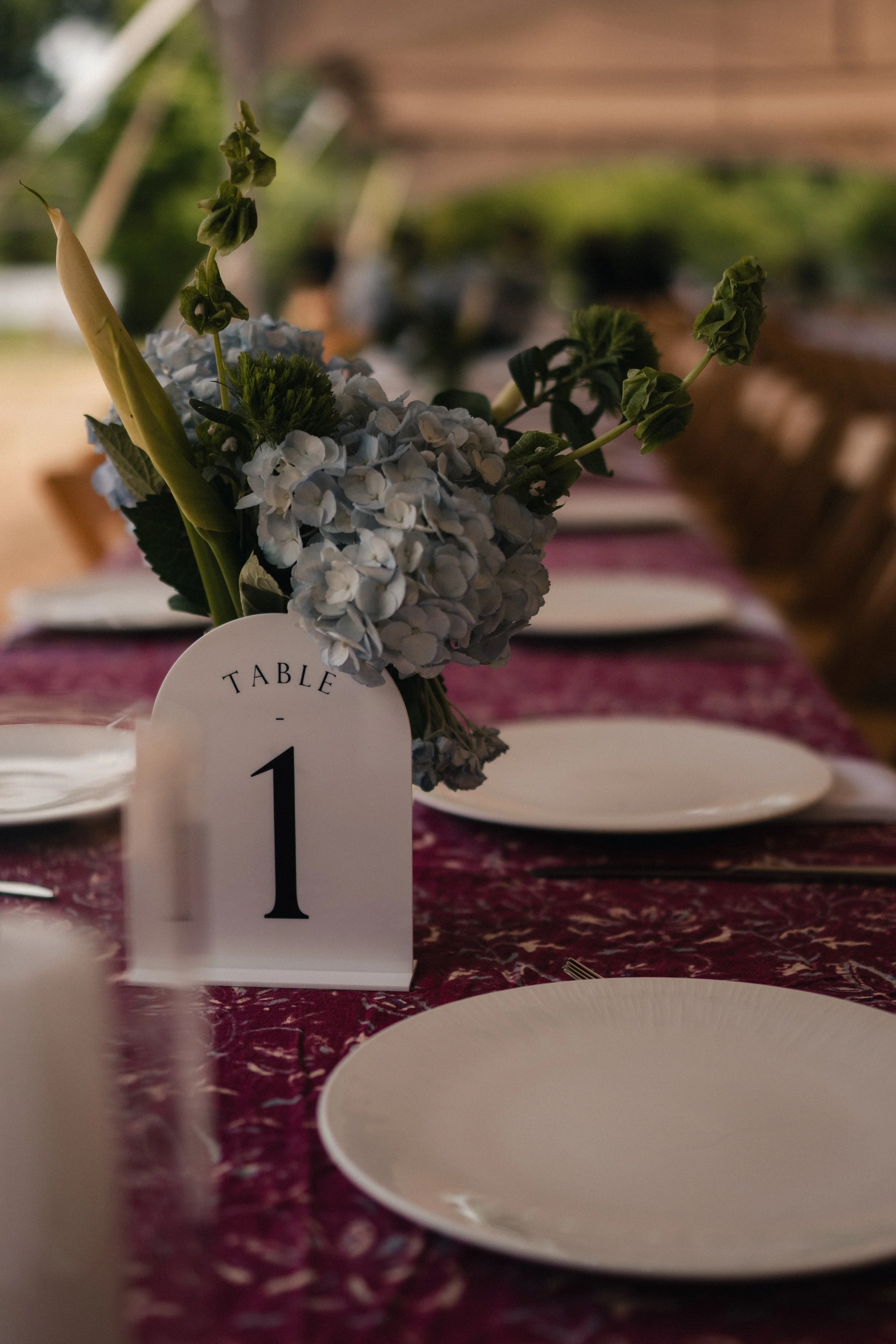 A table centerpiece featuring white and green flowers at a formal event, with table number 1 visible in the foreground on a white card.