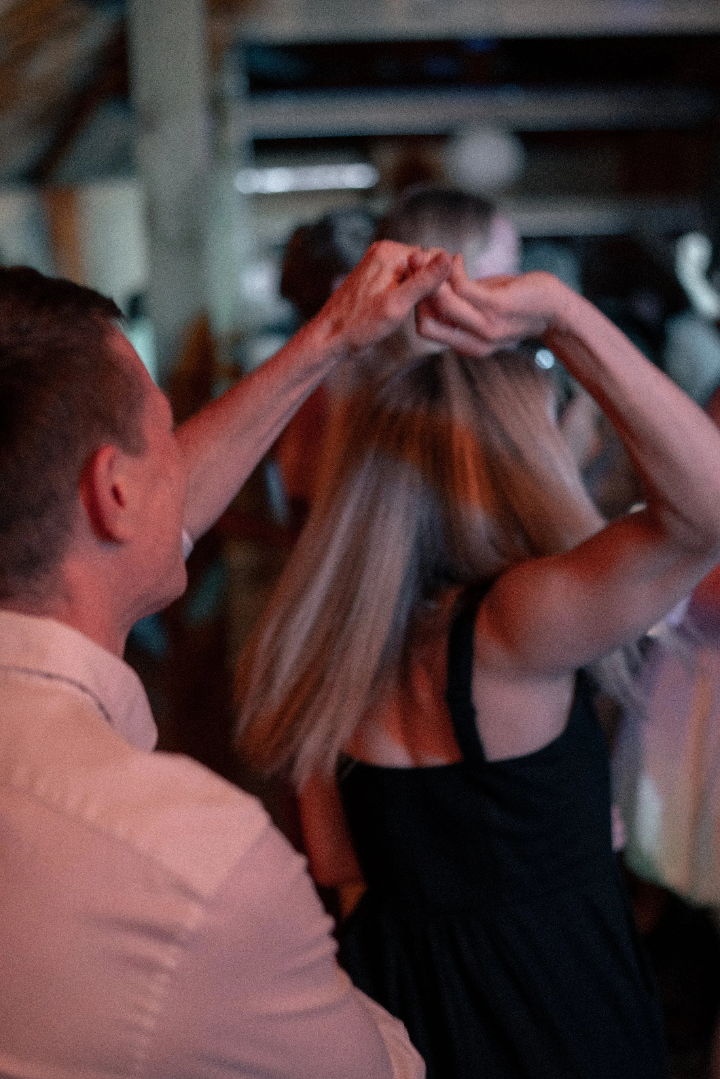 Blurred photo of people making a heart shape with their hands in an indoor setting.