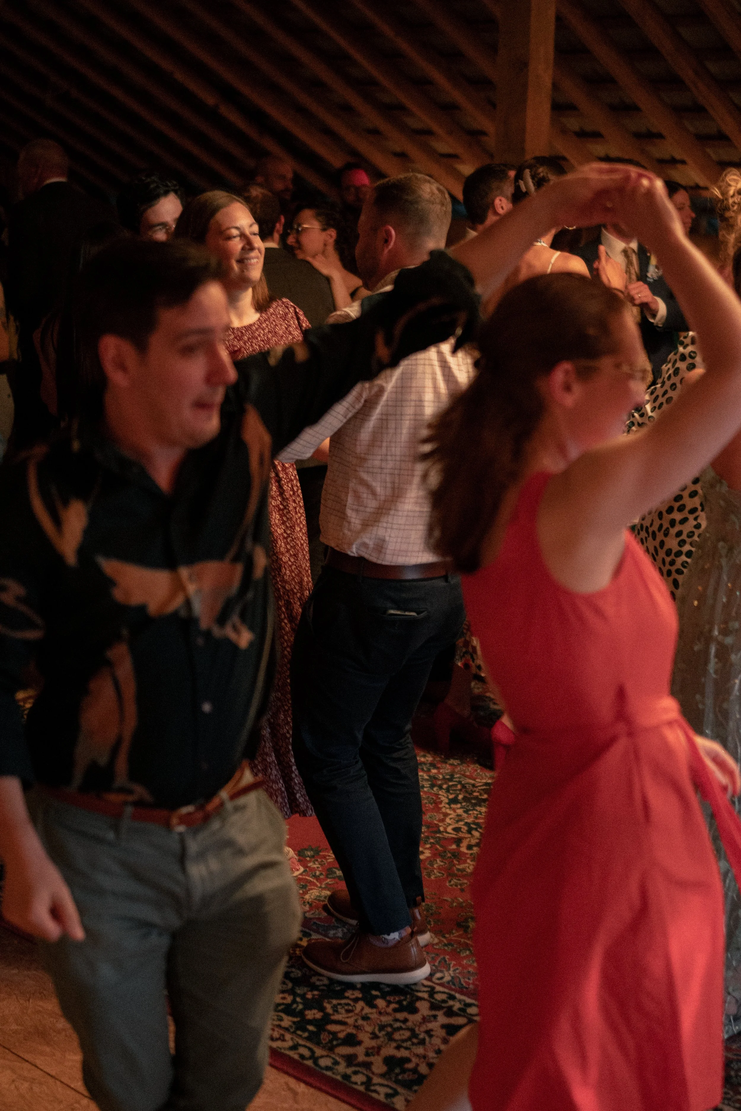 People dancing together at a social event or party in a rustic wooden indoor setting.