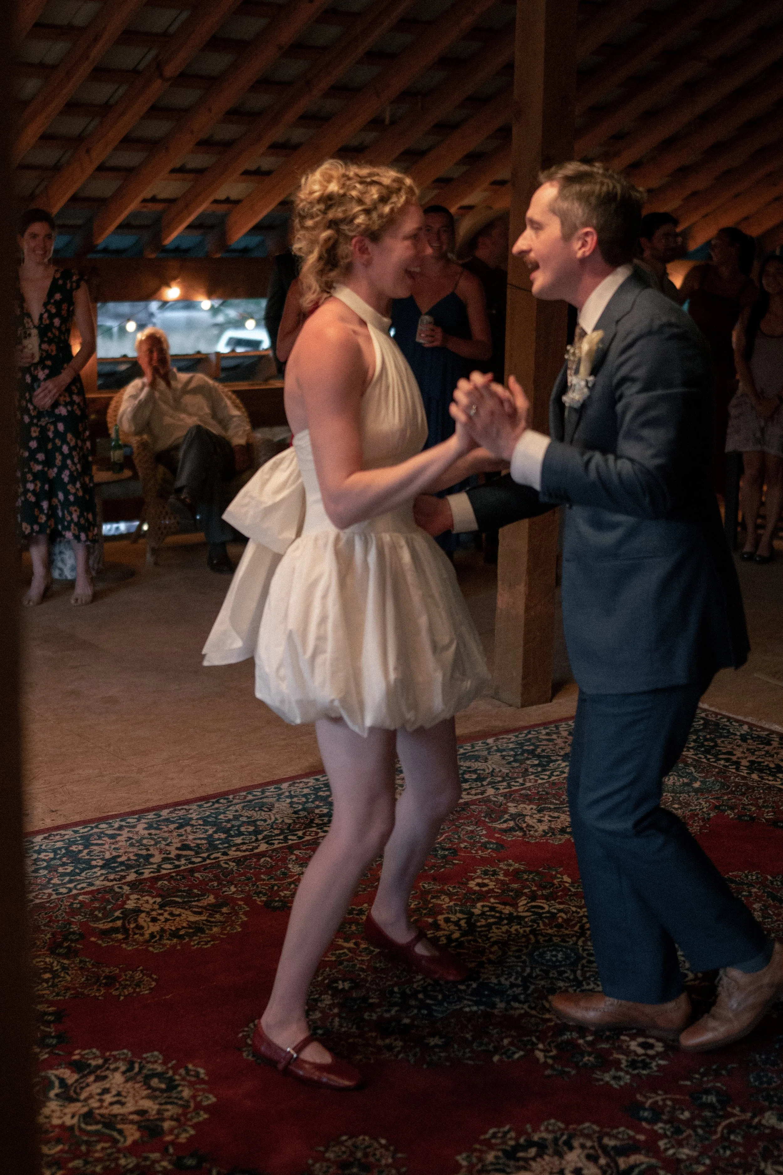 A bride and groom are dancing together during their wedding reception, holding hands and smiling.