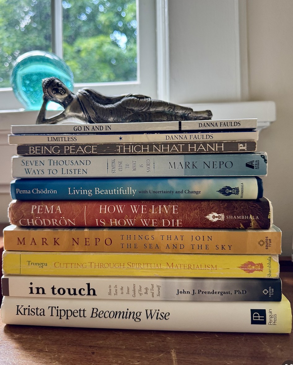Stack of Jillian Pransky’s summer reading books on mindfulness, presence, personal growth, and well-being, topped with a reclining Buddha statue.