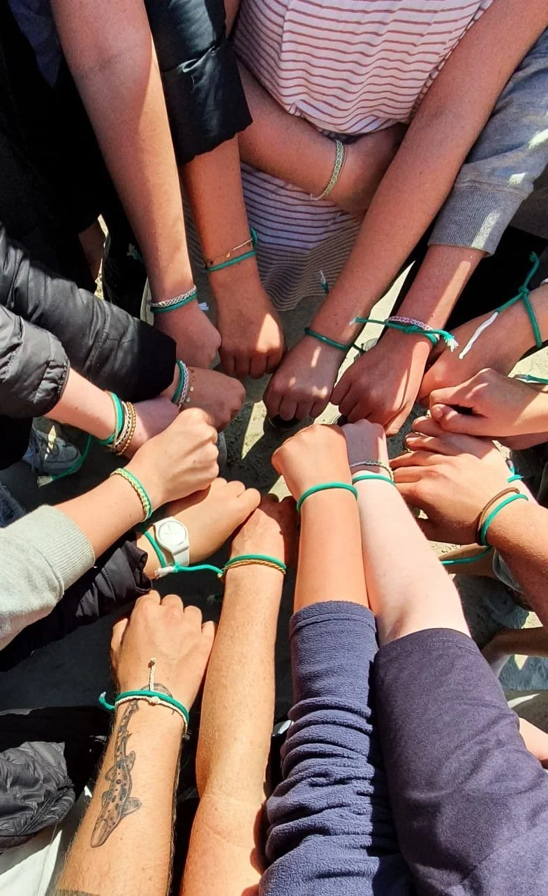 Team hands together with green wrist bracelets showing unity