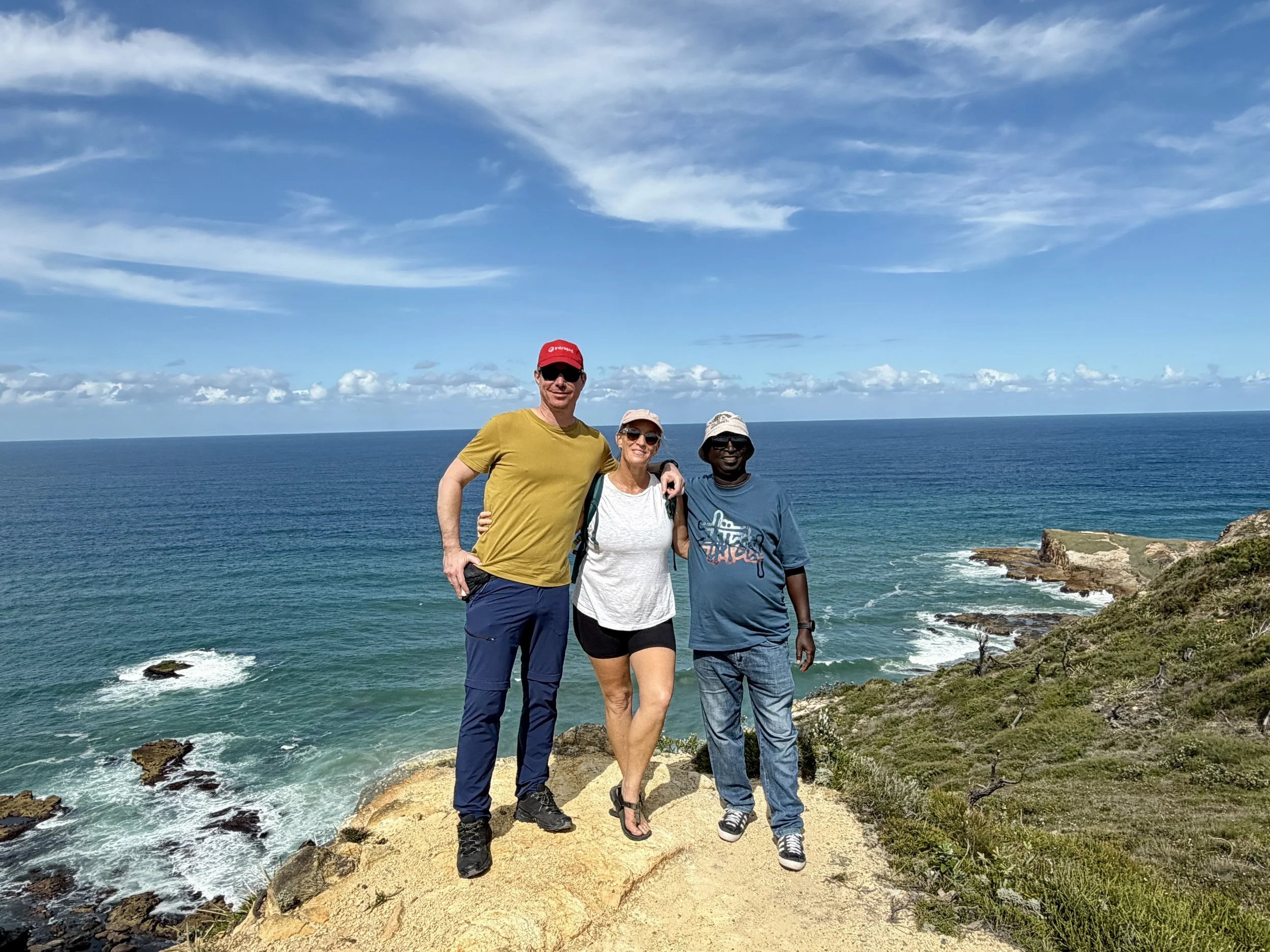 Three Intrepid tour guides standing one a cliff in Australia over looking the ocean