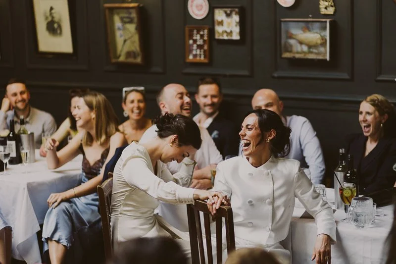 Candid wedding photography showing couple and guests laughing during speeches