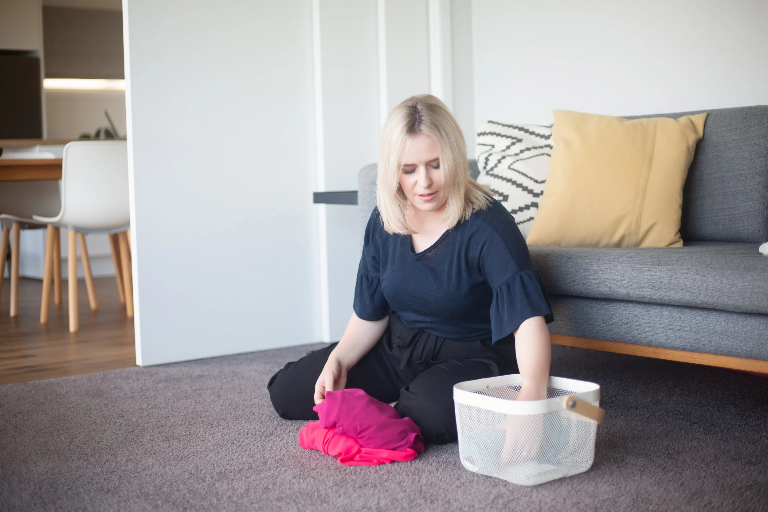 Alaina, A Wellington Housekeeper, Folding washing into a basket on the floor.