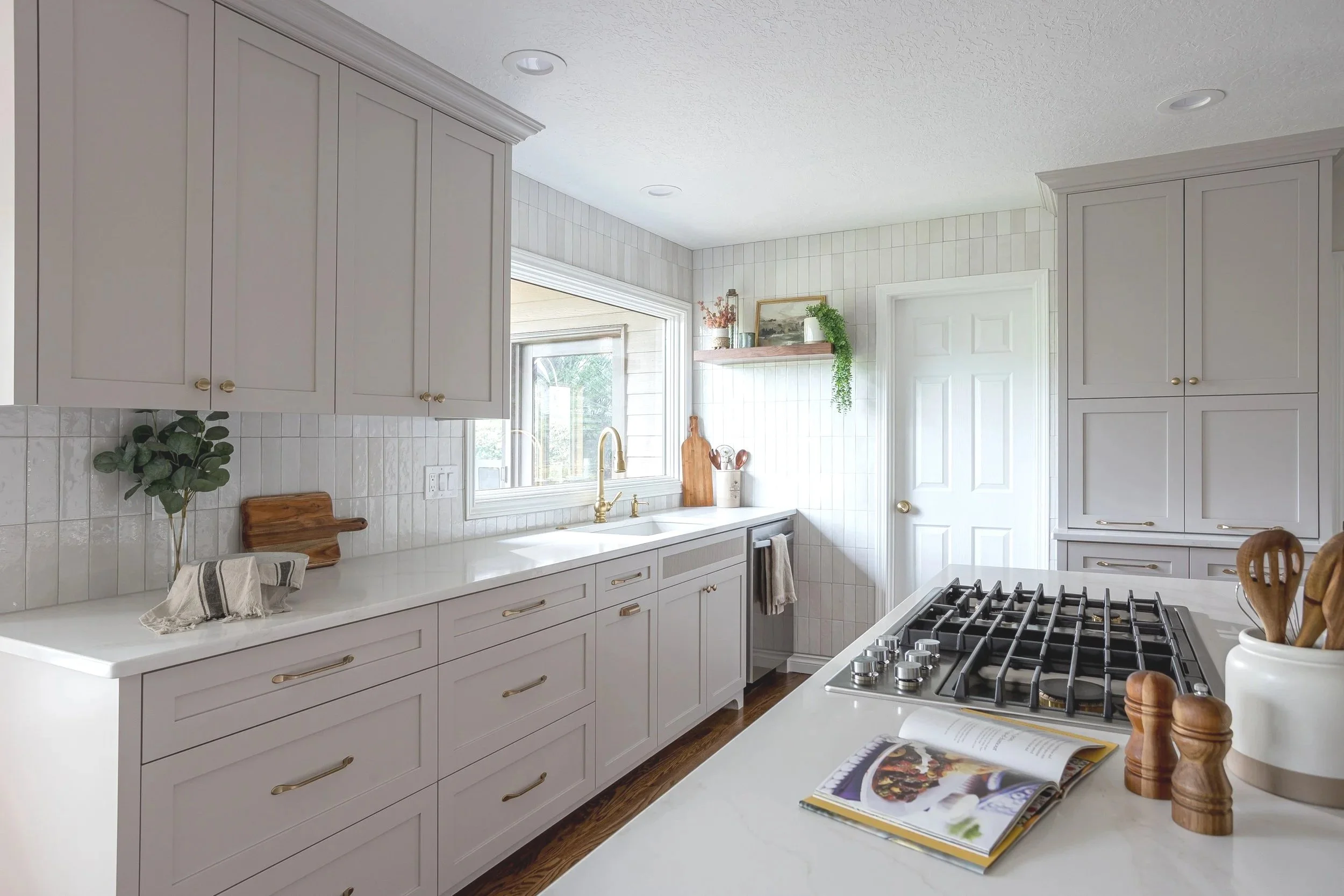 Custom kitchen remodel with white shaker cabinets, quartz countertops, integrated wall ovens, warm wood flooring, and a spacious island designed for efficient workflow and everyday living in a Portland, Oregon home.