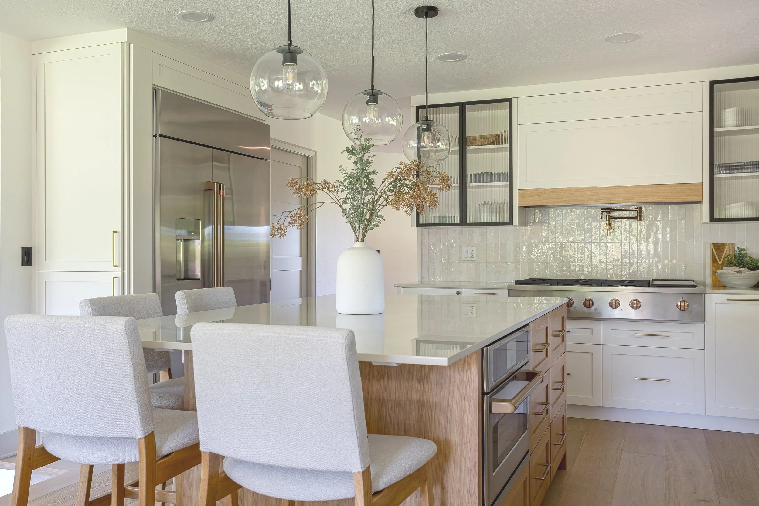 Modern kitchen remodel with white cabinetry, wood island, quartz countertops, globe pendant lighting, and stainless steel appliances in a bright, welcoming home.