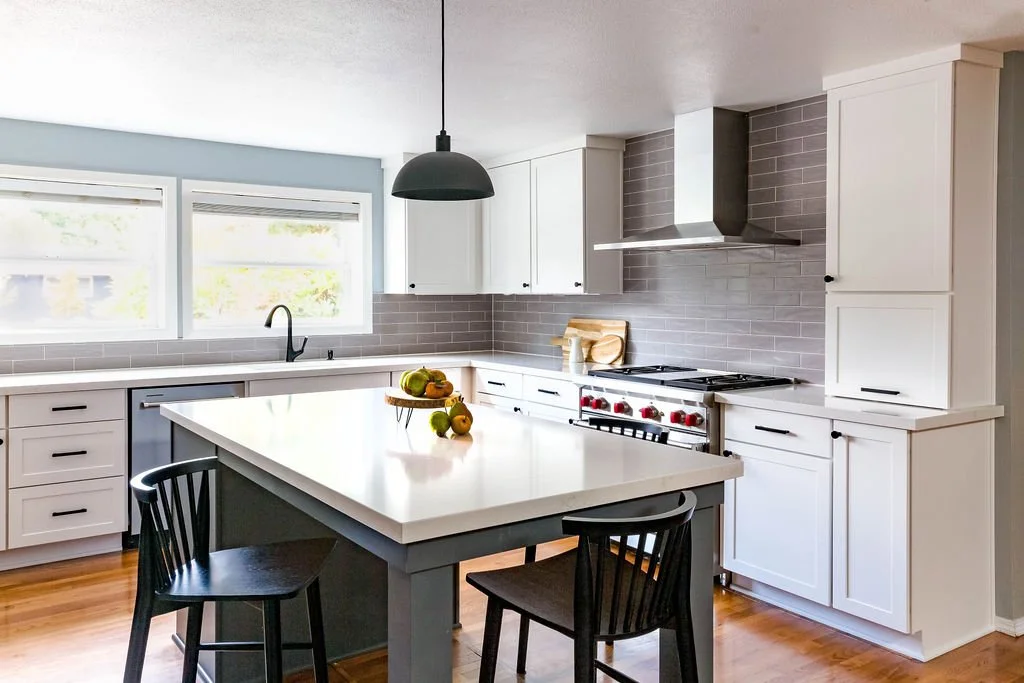 White kitchen remodel with gray subway tile backsplash, stainless steel gas range, custom vent hood, and quartz countertops in a Portland Oregon home.