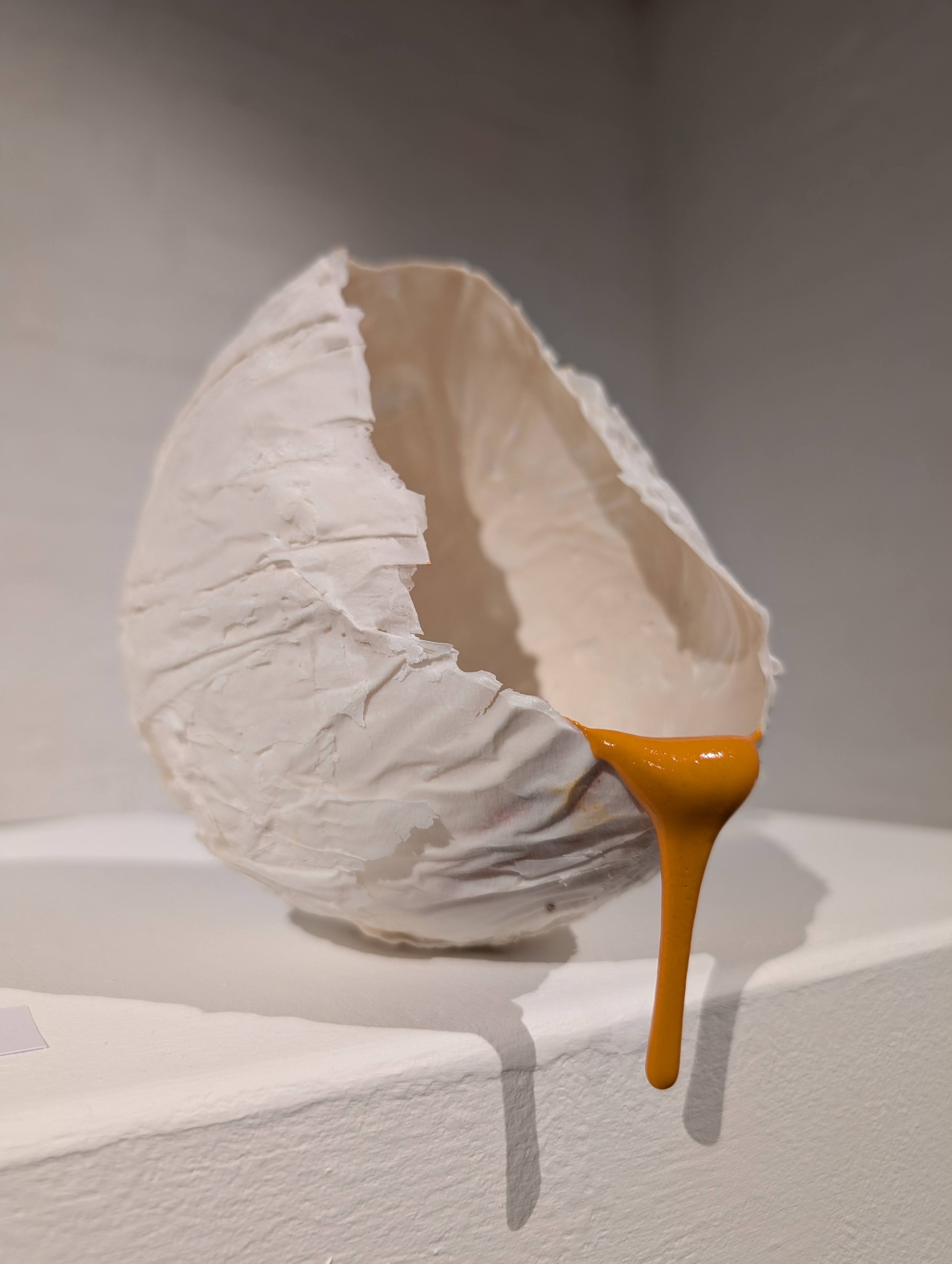 Porcelain form with orange gloop glaze hanging over the side