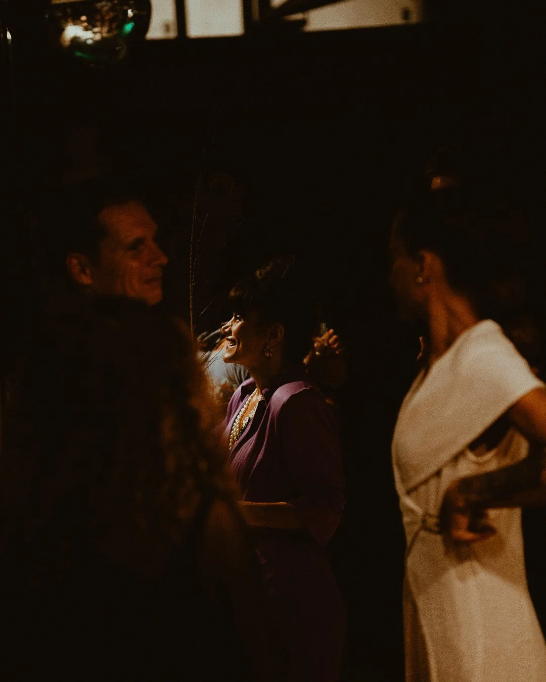 People dancing and enjoying music at a dimly lit party or social gathering.