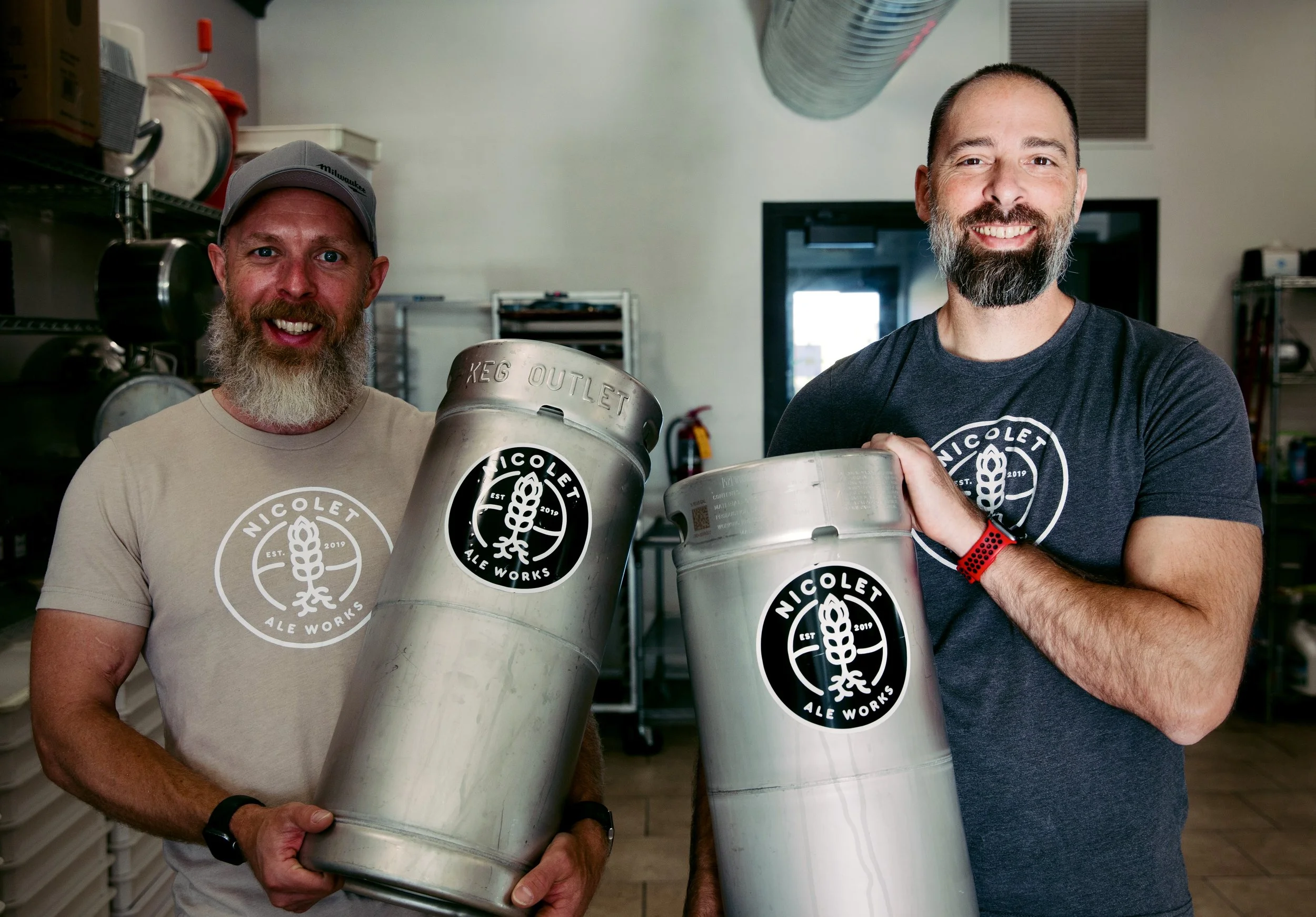 Nicolet Ale Works founders Jeremy Voss and Ben Rank holding beer kegs at the brewery in De Pere, Wisconsin.