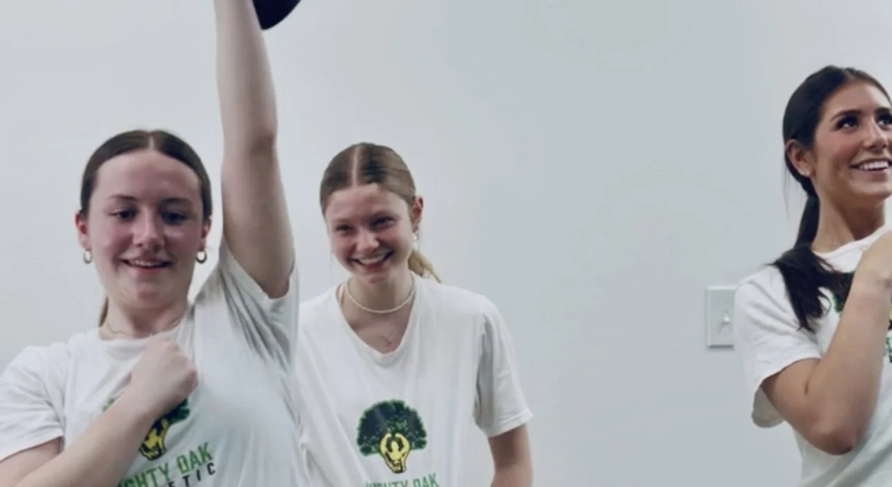 Smiling teen girl training with instructor at Mighty Oak Athletic gym in DuPage County