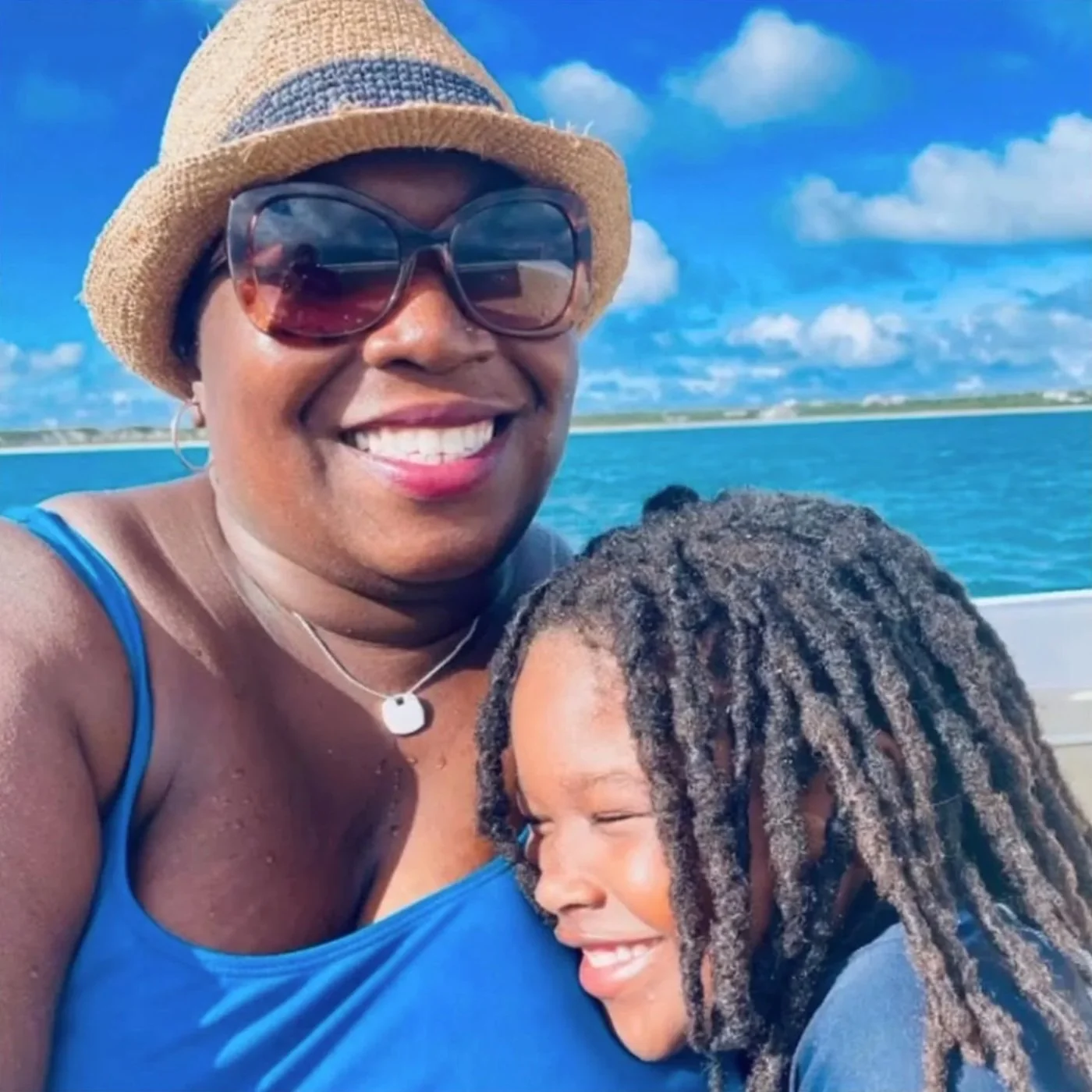 Family smiling aboard a GoodLiving Charters boat cruising turquoise Caribbean waters off Anguilla.