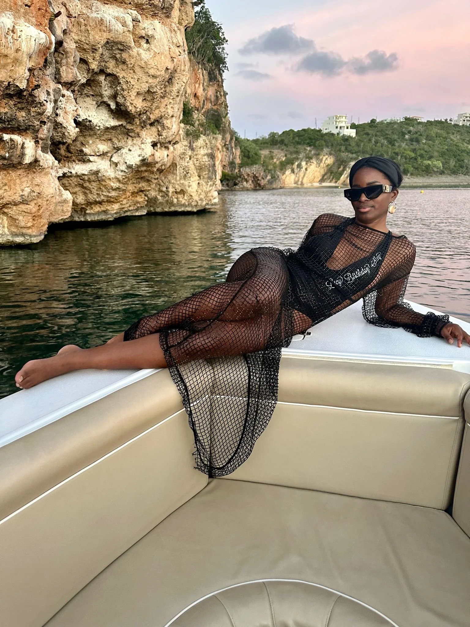 Guest relaxing on a private GoodLiving Charters sunset cruise at Little Bay, Anguilla, with golden cliffs and soft evening skies reflected on the calm Caribbean water.