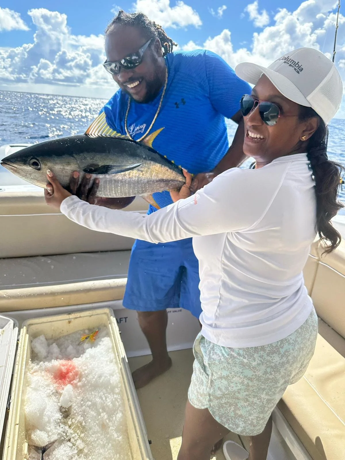 Captain Jel and a guest share a laugh while holding a freshly caught yellowfin tuna aboard a GoodLiving Charters boat during a sunny fishing trip in Anguilla.