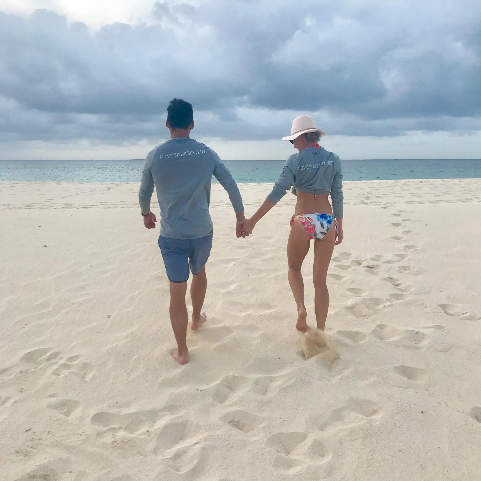 Couple walking hand-in-hand along an Anguilla beach at sunset on a GoodLiving Charters cruise.