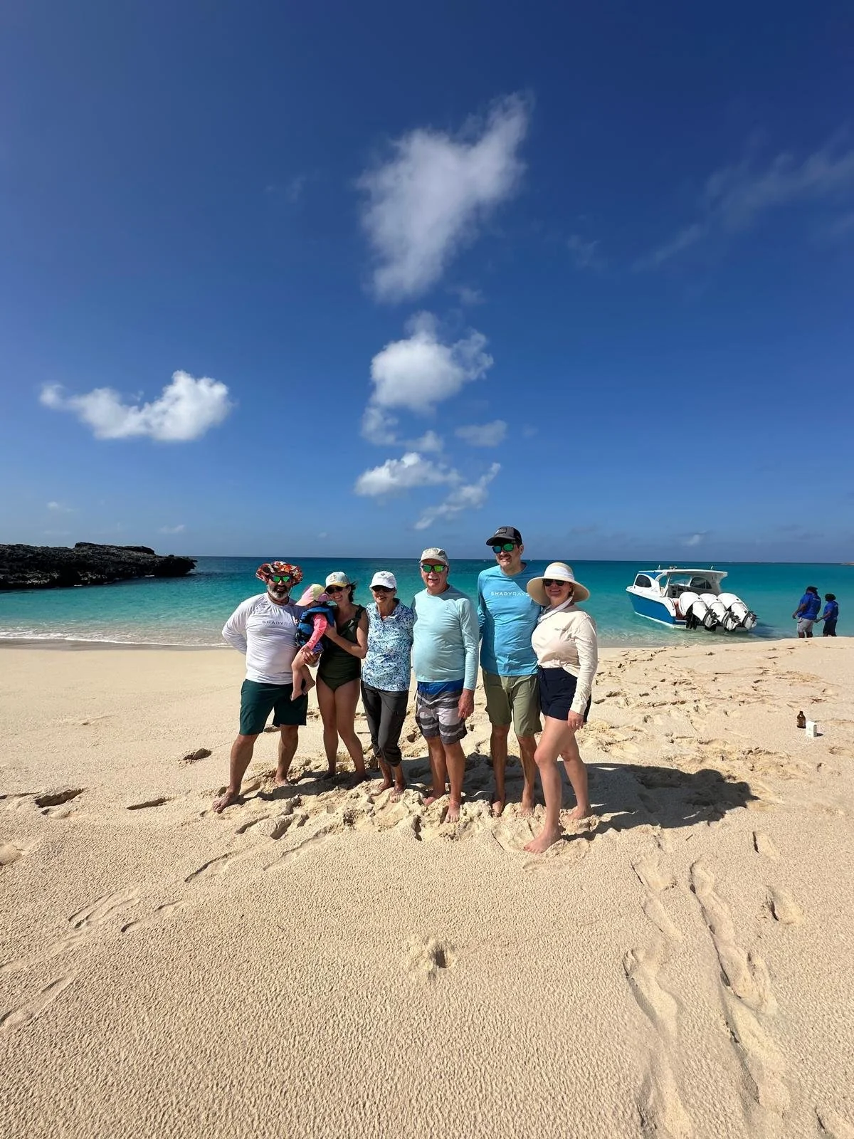 Family group posing on a sandy beach with private boat in Anguilla