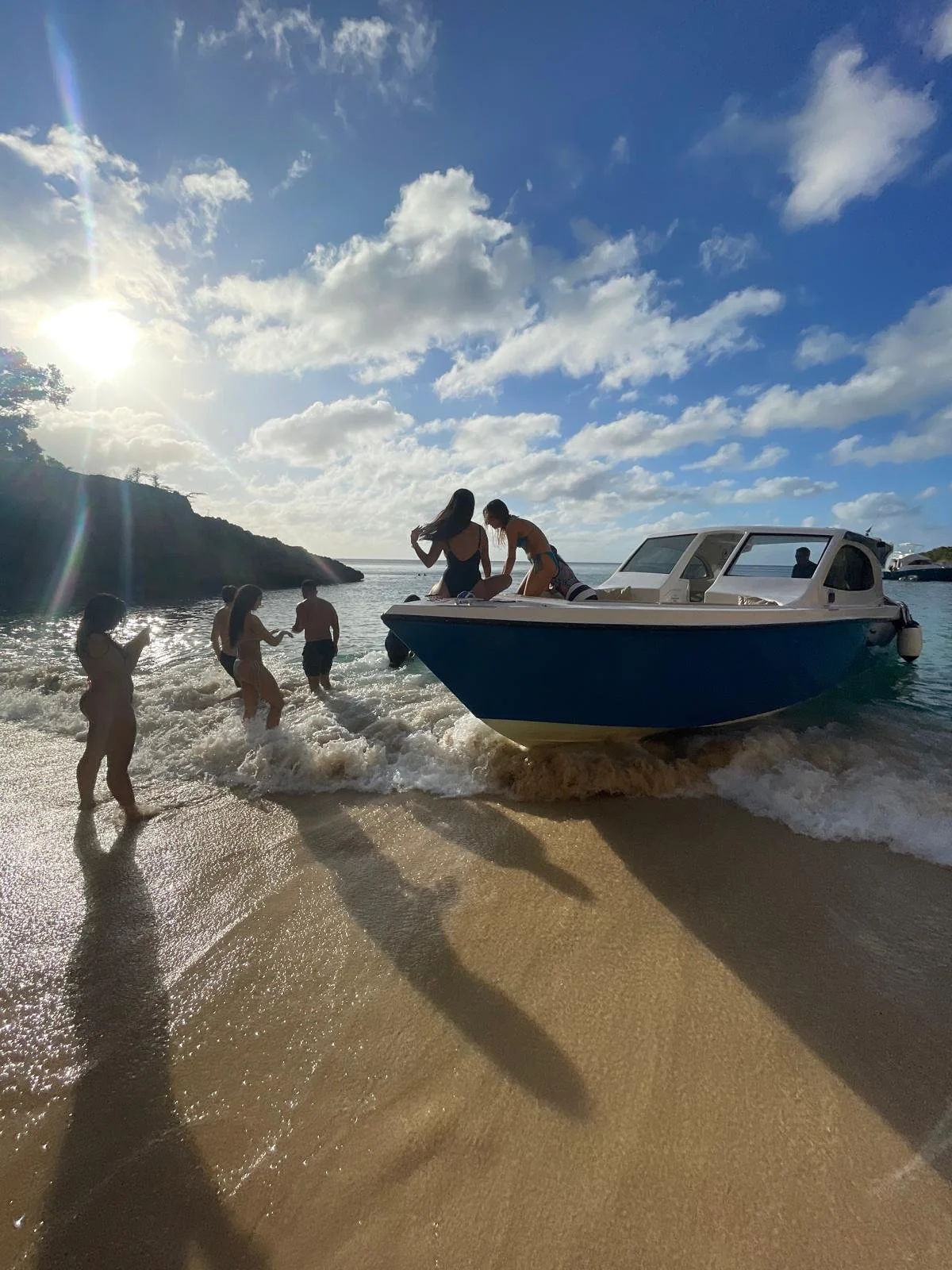 Guests enjoy a private GoodLiving Charters excursion at Little Bay, Anguilla, stepping off the blue GoodLiving boat onto the sandy beach under a bright Caribbean sky.