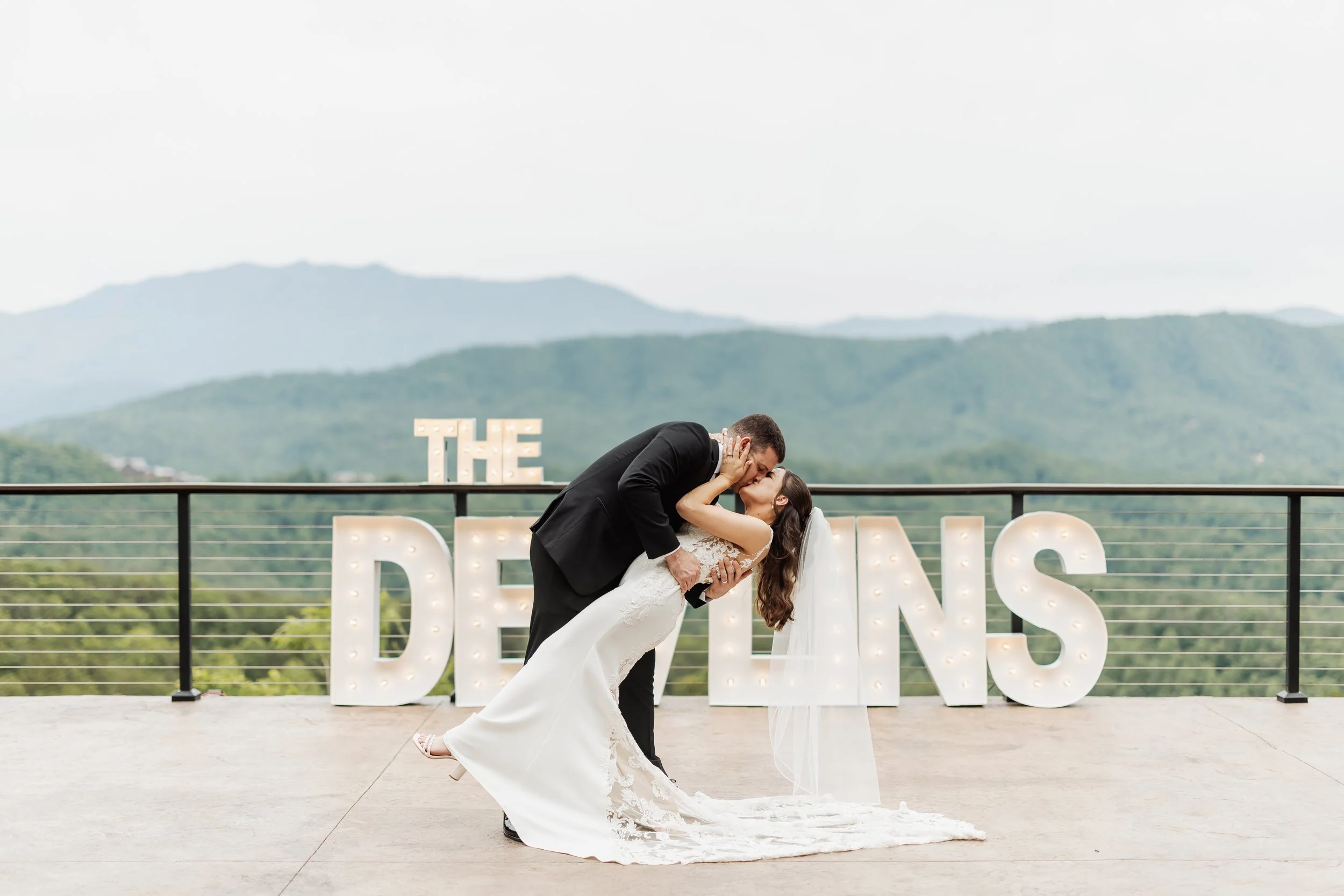 A couple dips in front of their name sign at their venue.