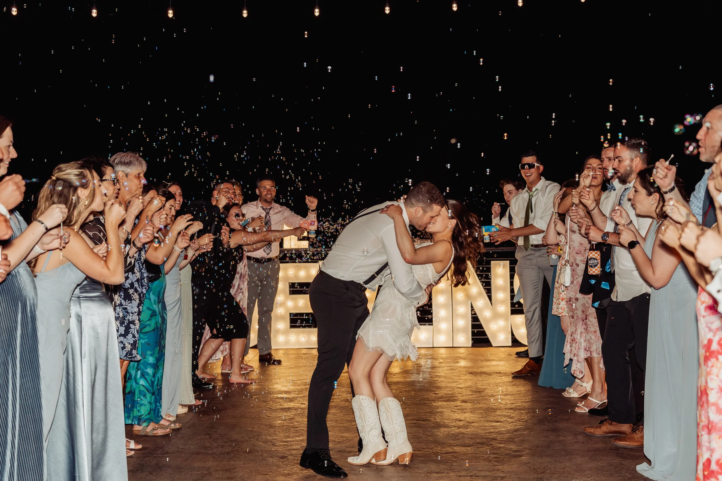 This exit photo shows the couple kissing in the middle surrounded by bubbles.
