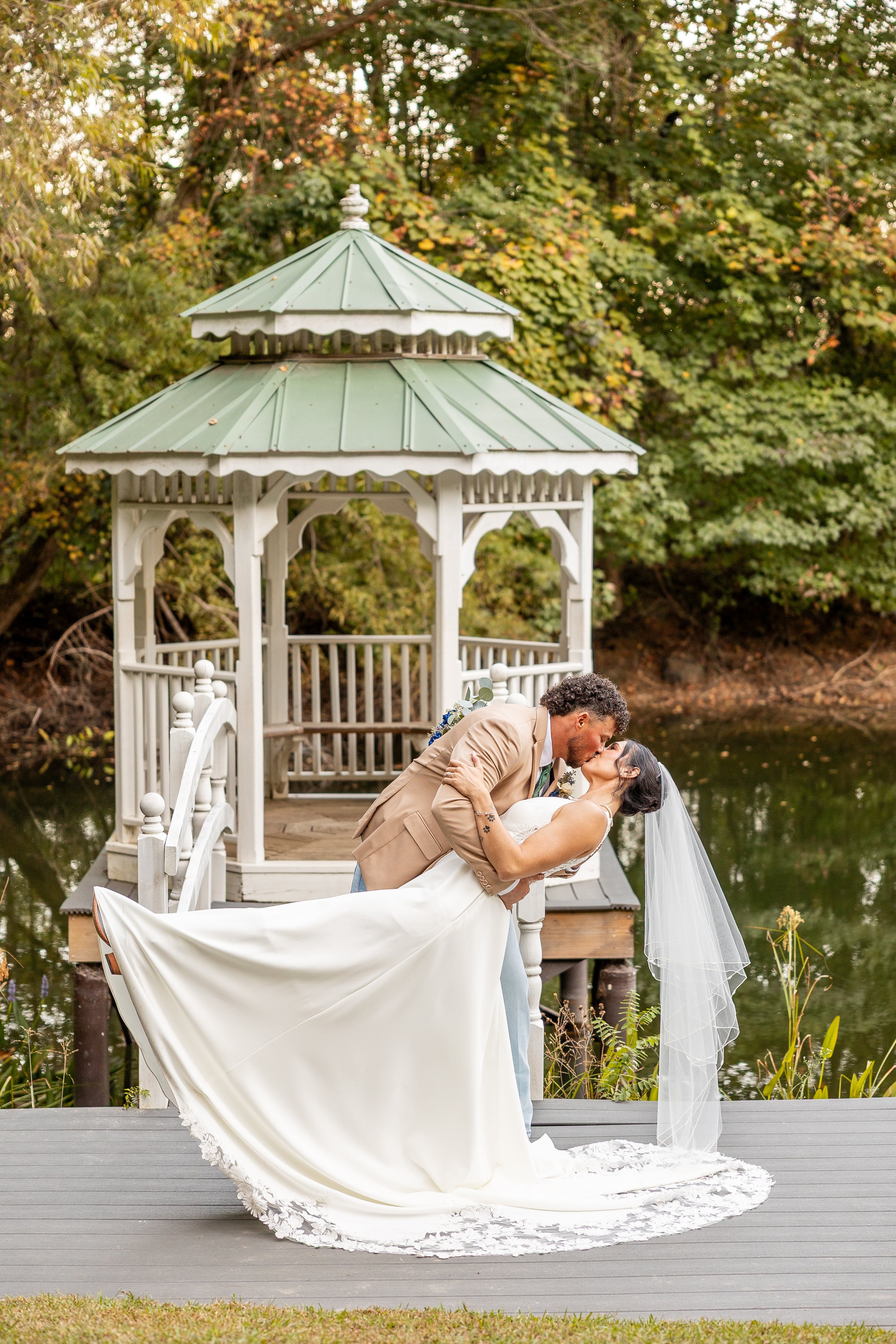 The bride and groom dip outside of the gazebo on the lake.