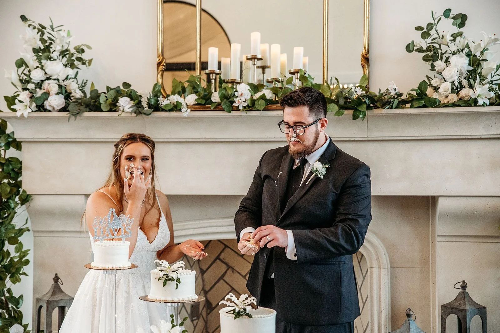 A bride and groom finish a cake smashing with cake all over their faces.
