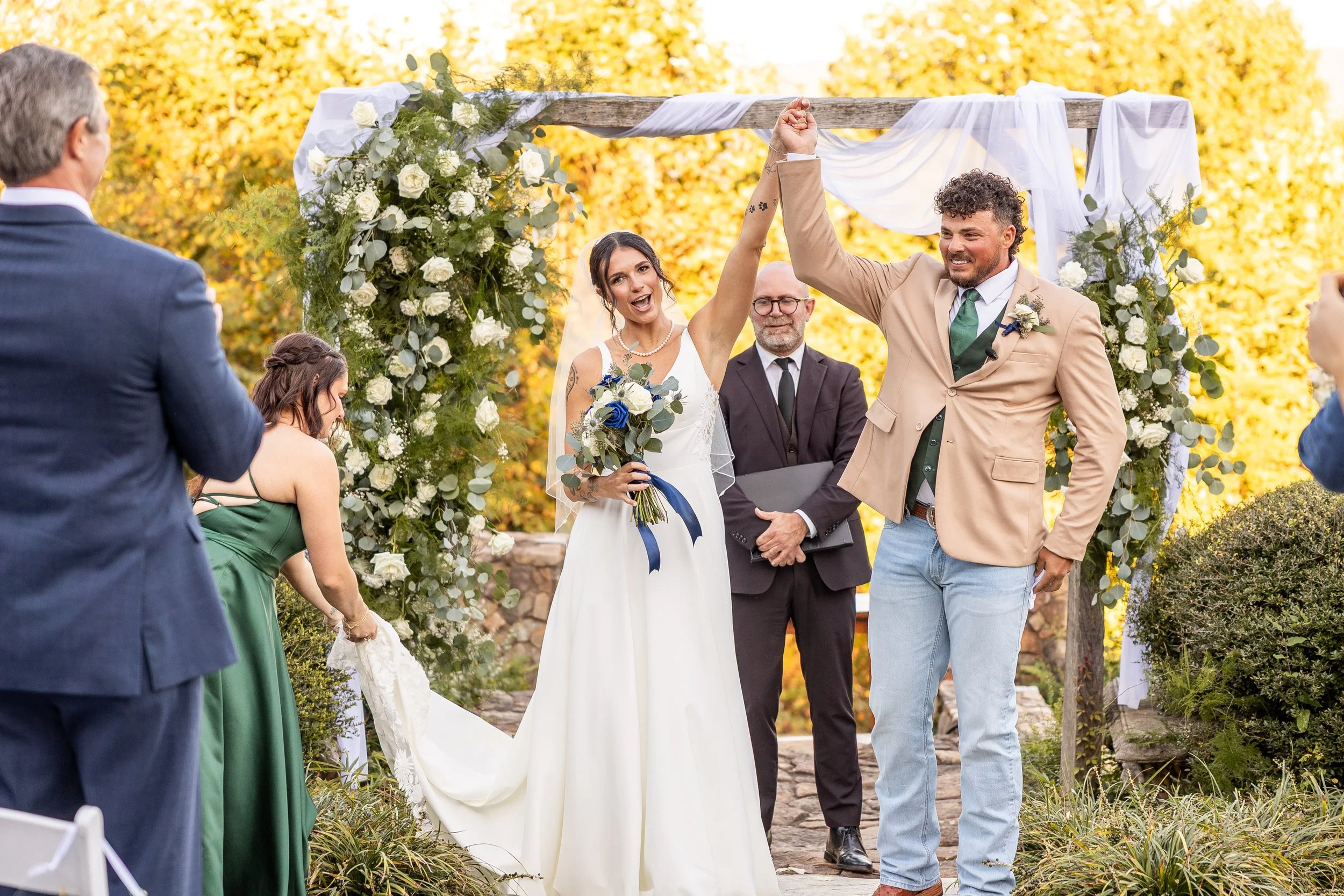 A couple raises their hands together celebrating the end of their ceremony.