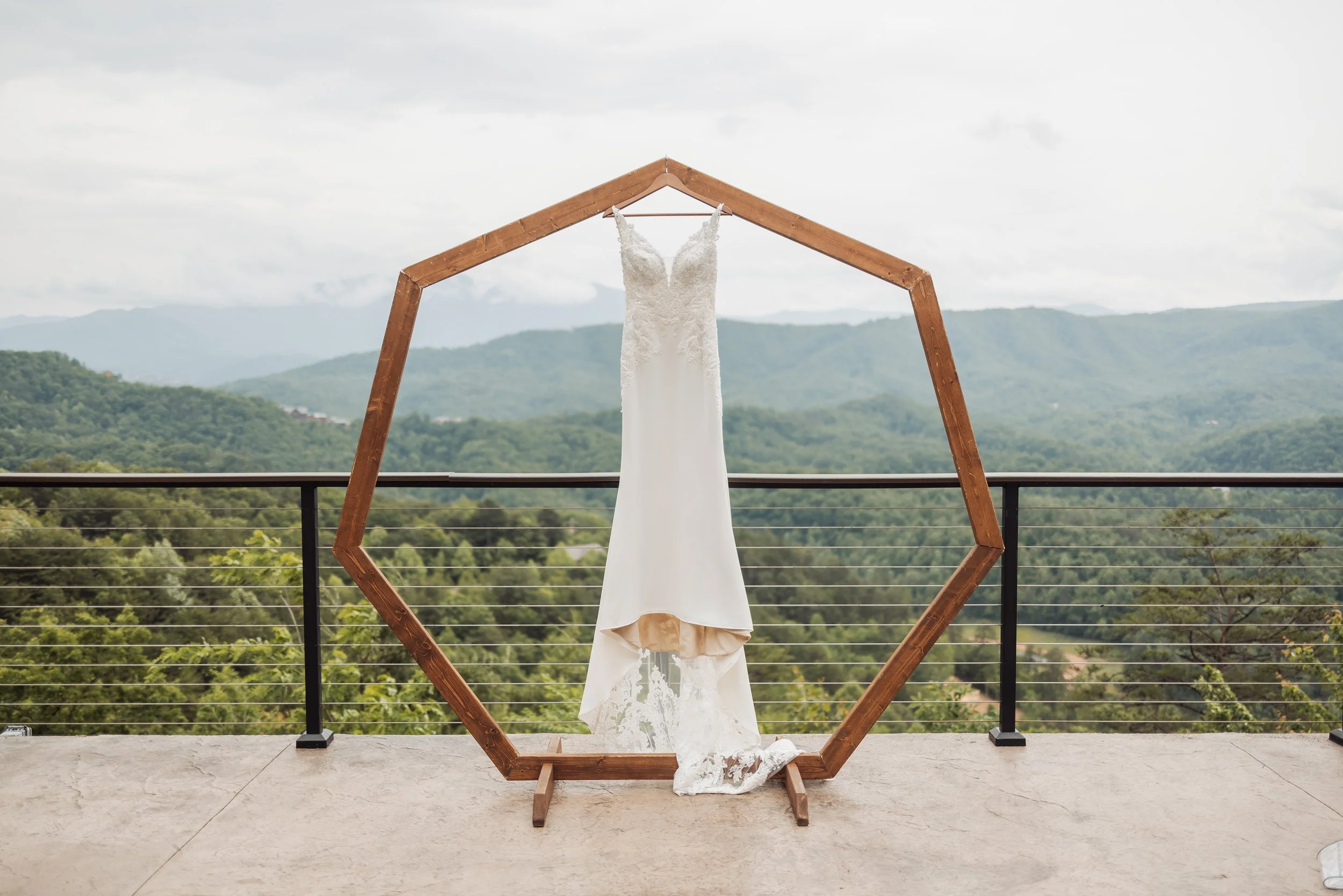 The bride's wedding dress is hanging on the ceremony arch.