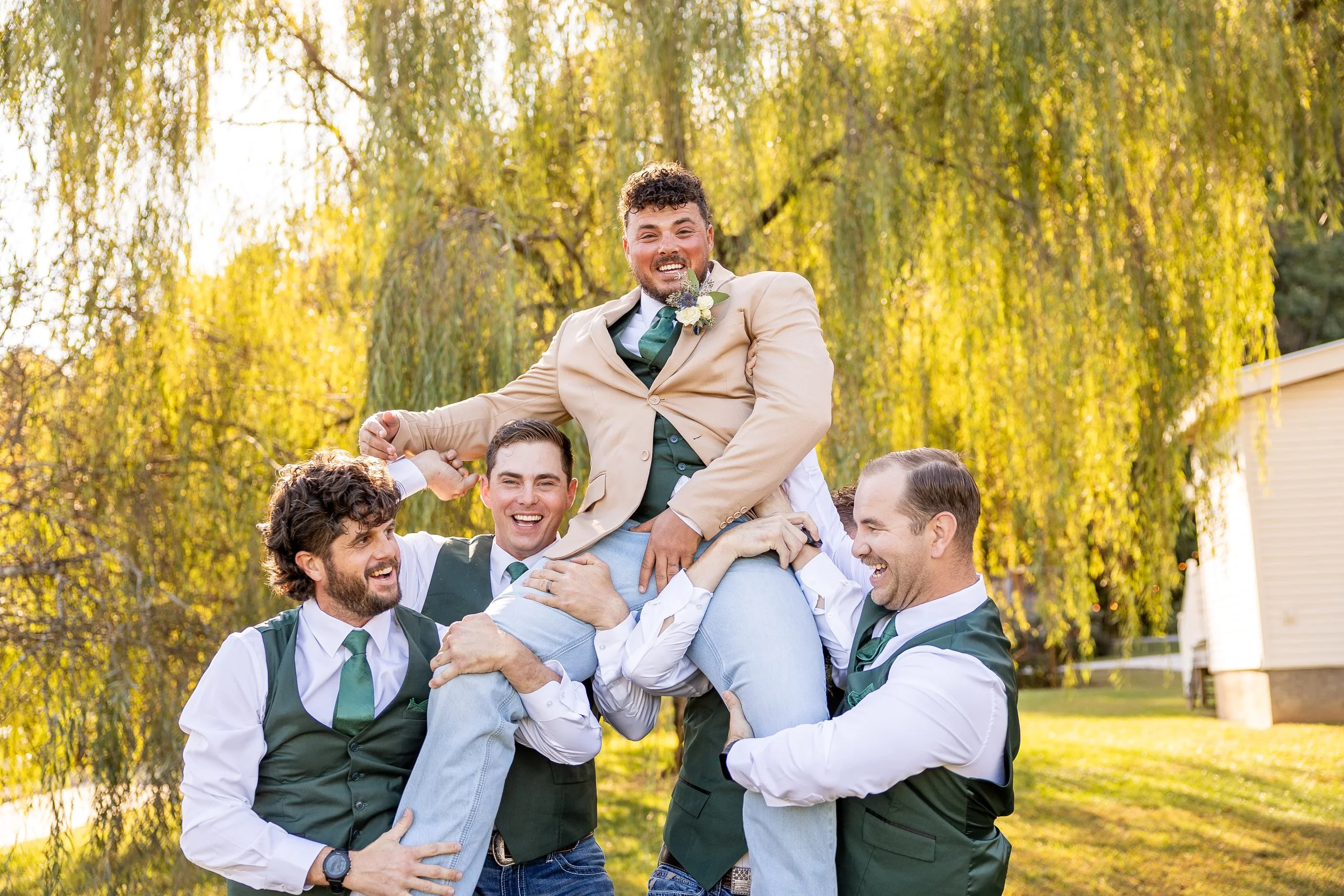 Groomsmen lift the groom up into the air.