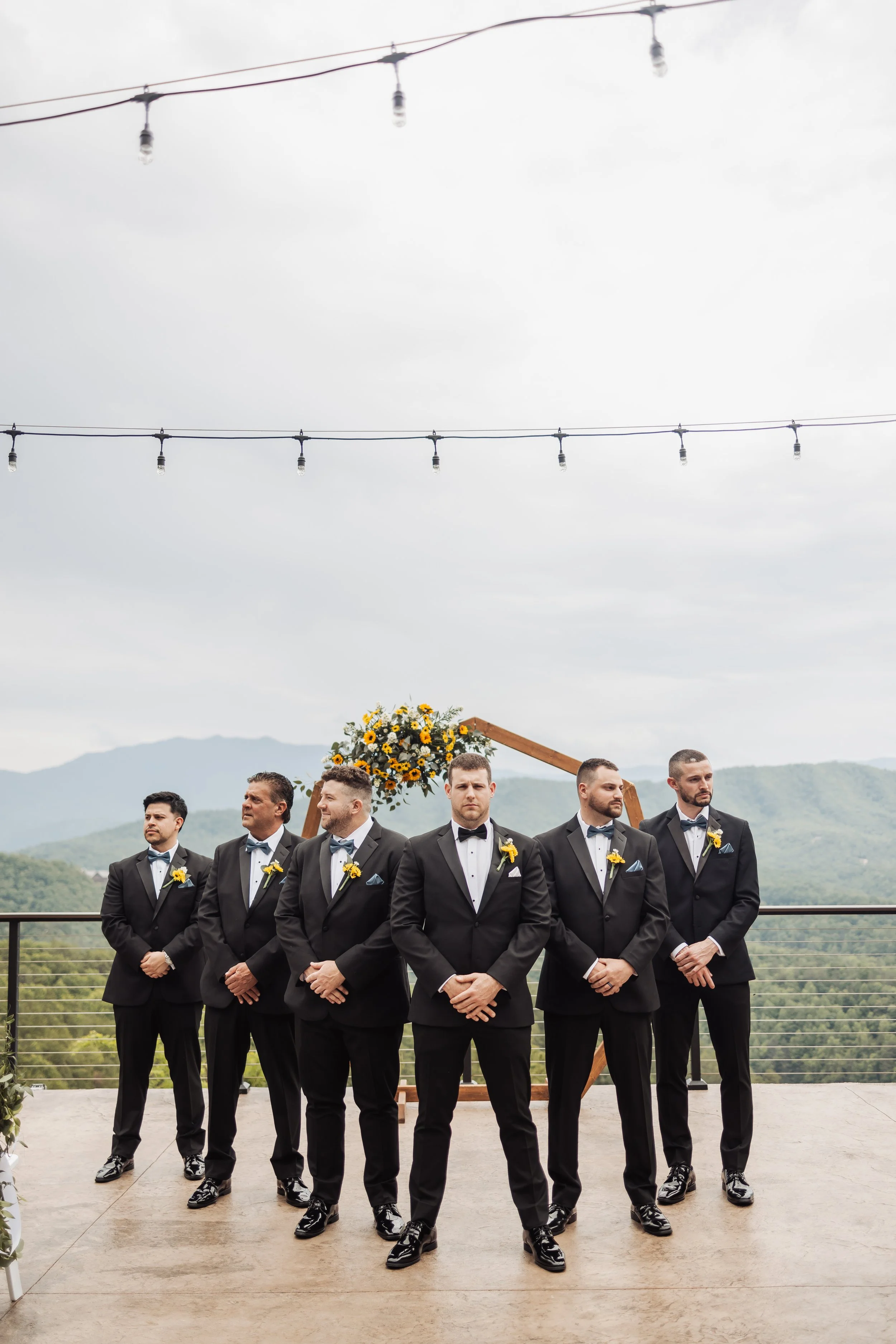 The groomsmen stand by the ceremony arch posing for a group photo.