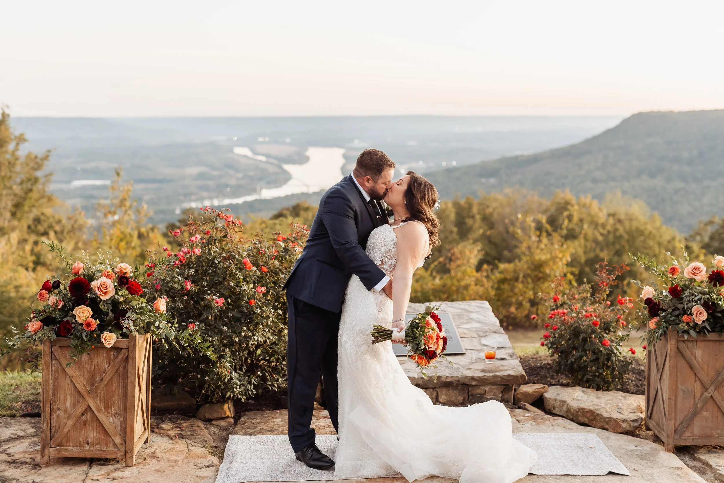 The couple kisses in front of the mountains at Pat's Summit.