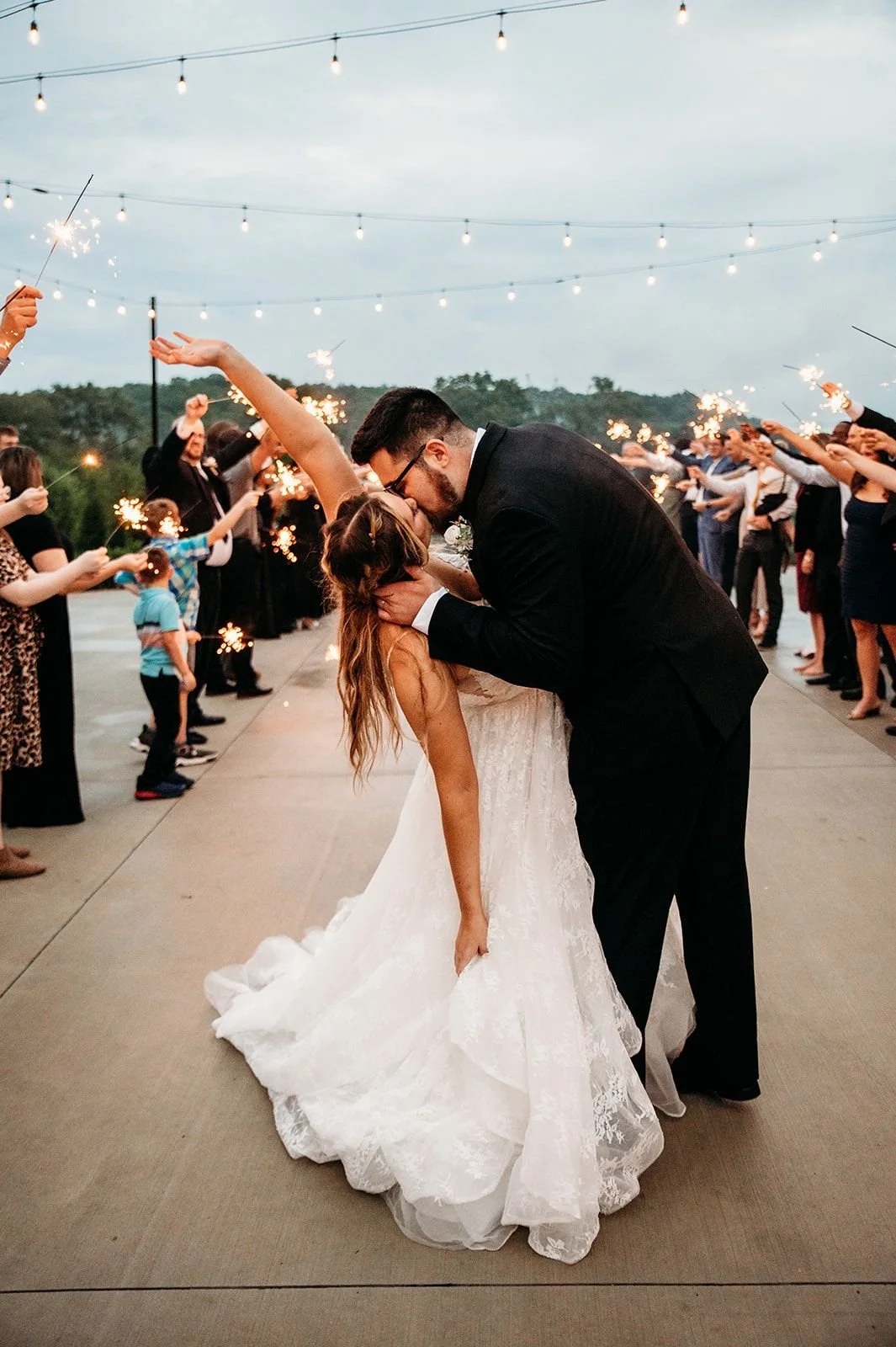 A couple leaves the Woodlands with a sparkler exit surrounded by family and friends.