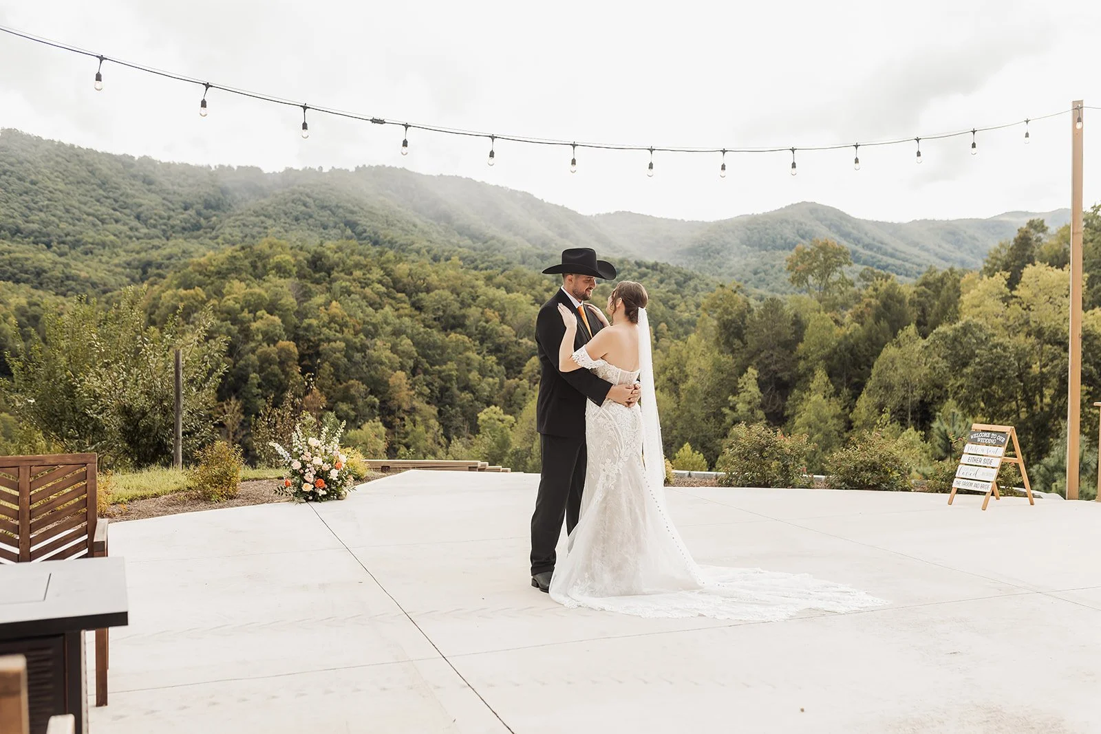 The couple stands on the dance floor for their first dance in front of the mountains.