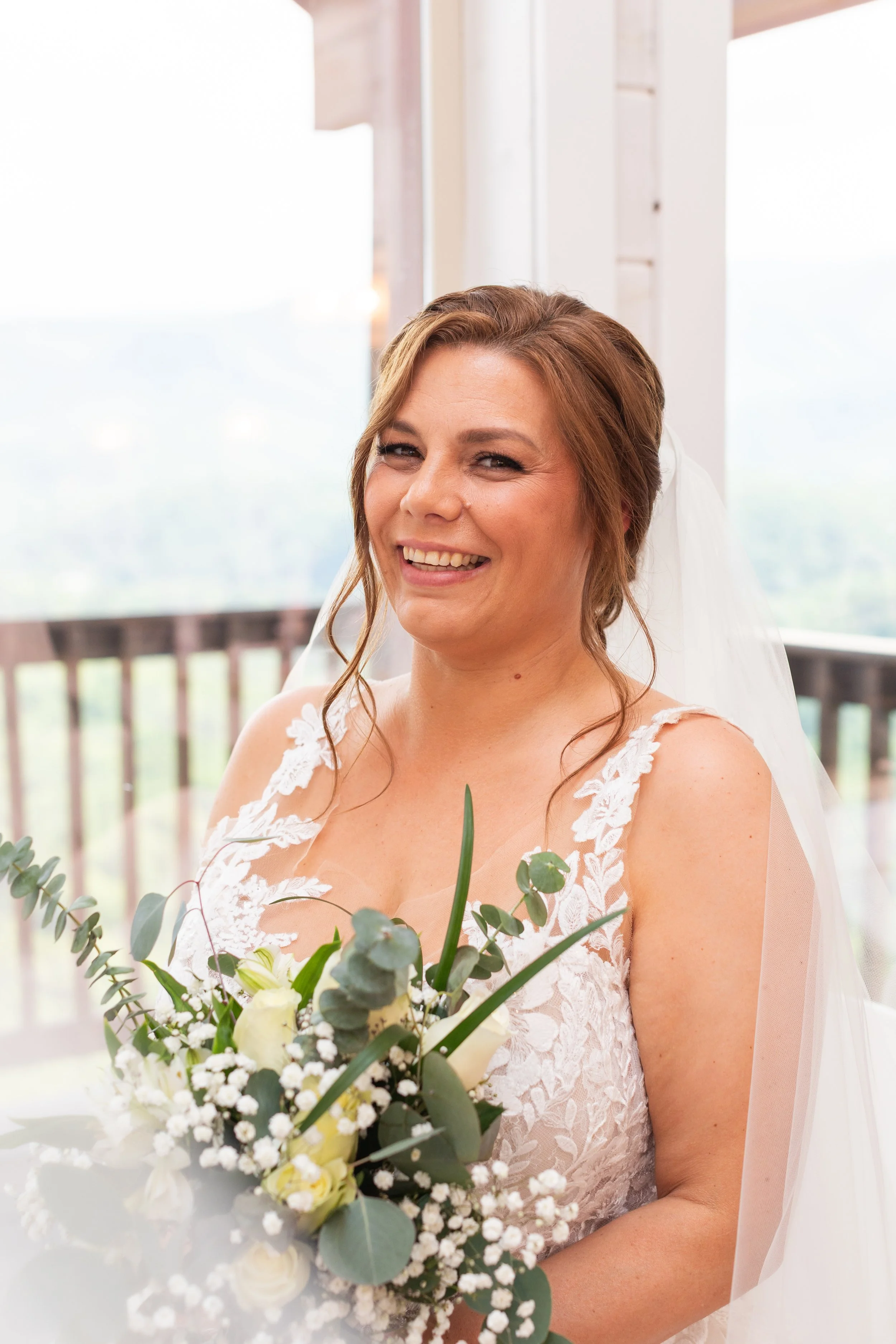 A bridal portrait of a bride standing in front of a window.