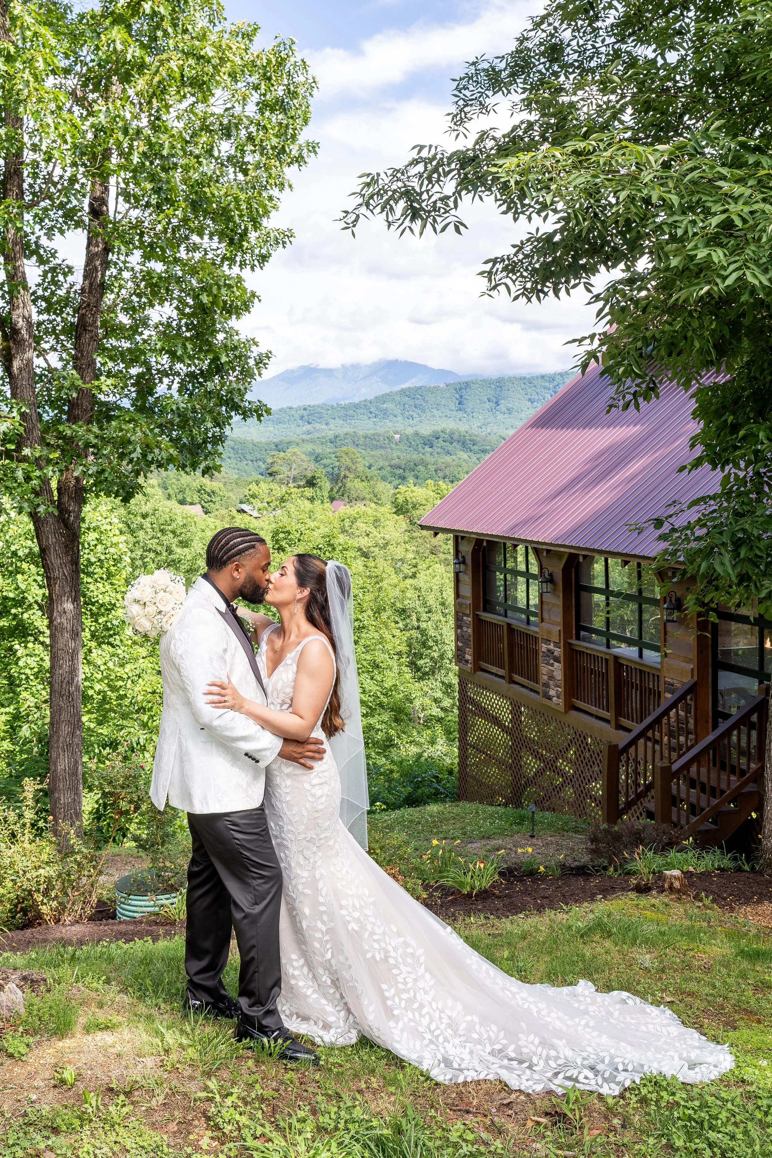 The newlyweds kiss in front of the cabin.