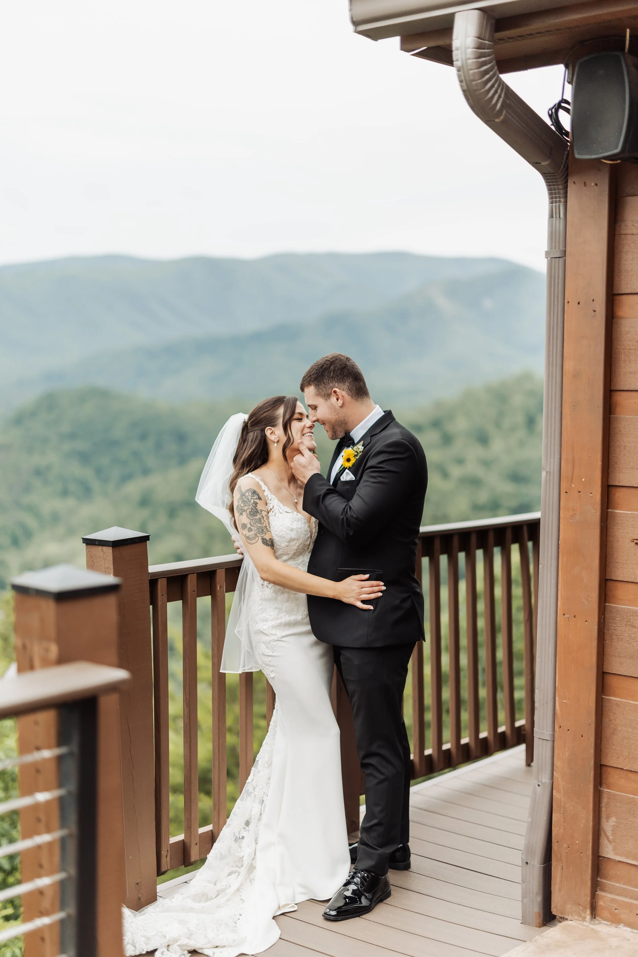 A couple is standing by the railing of the Magnolia cabin wedding venue.