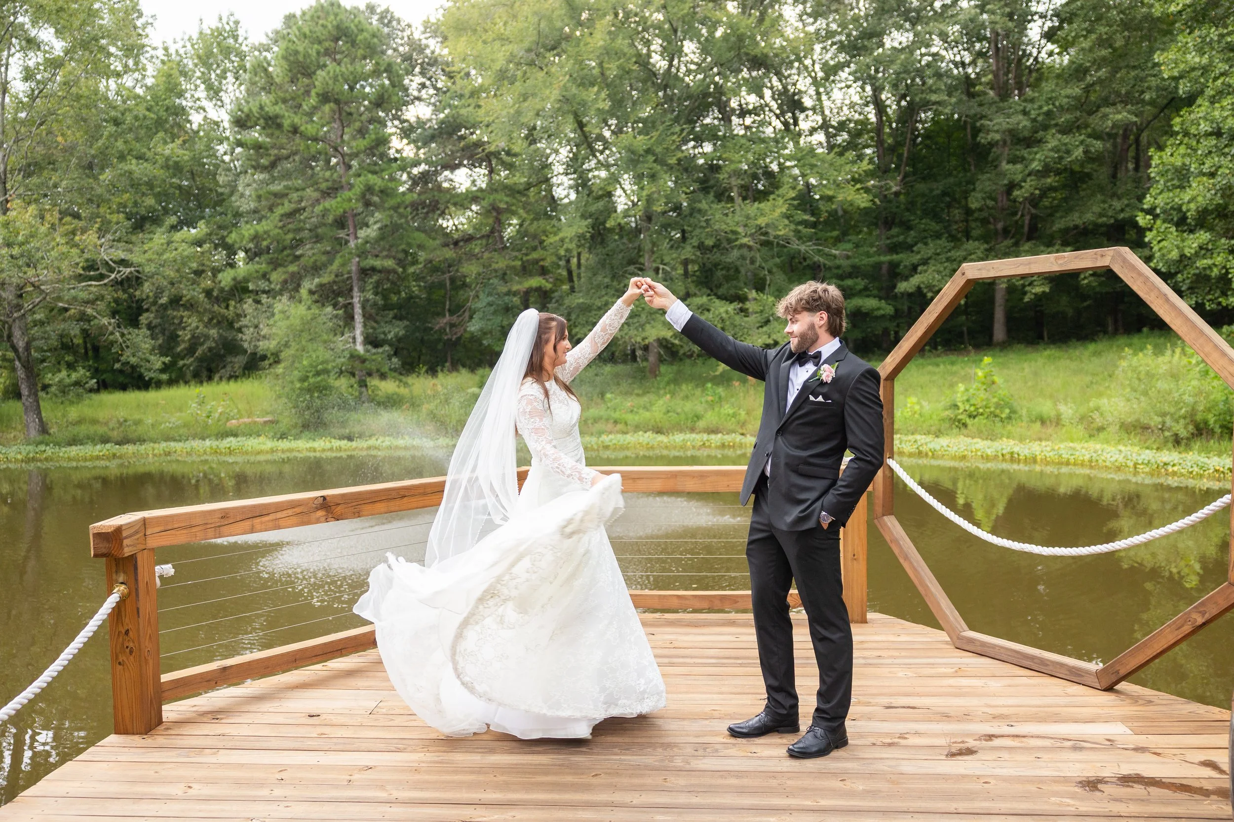 Newlyweds dance on the dock at the lake.