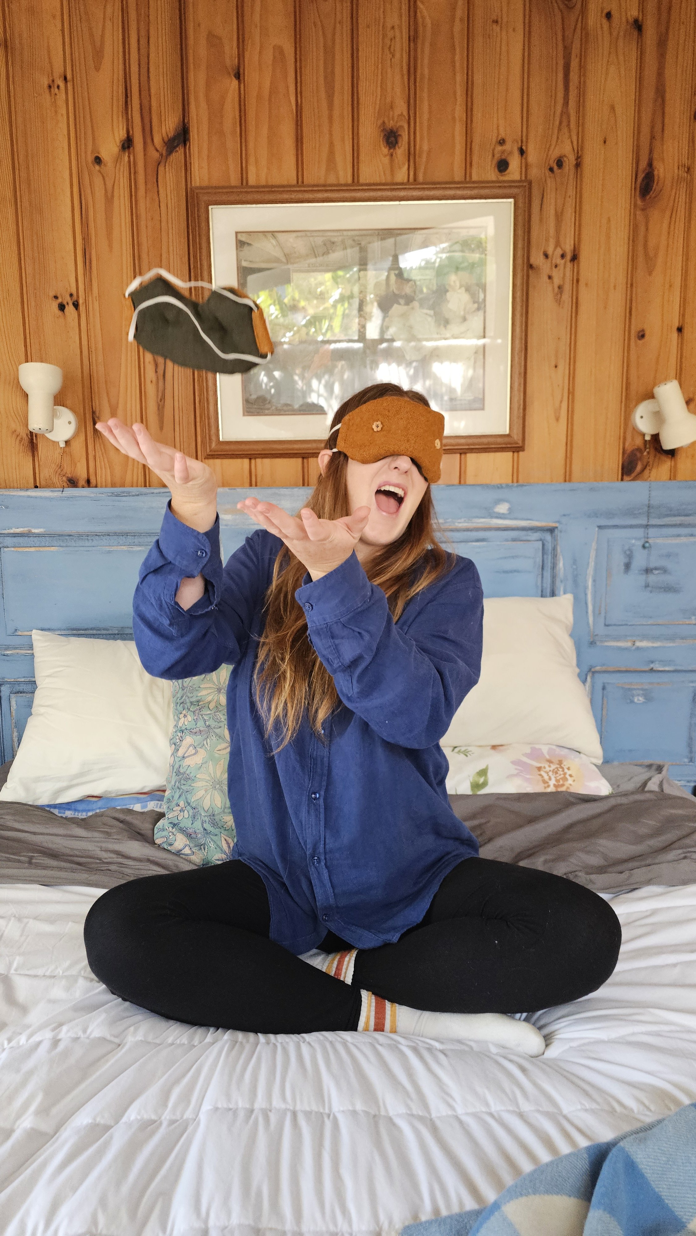 Kate Hall / Ethically Kate laughing while tossing the limited-edition Orchard Orange weighted eye mask into the air, celebrating the playful and practical side of protecting your sleep with the Ethically Kate × Do Not Disturb collaboration.