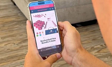 Hand holding a smartphone displaying a golf game app.