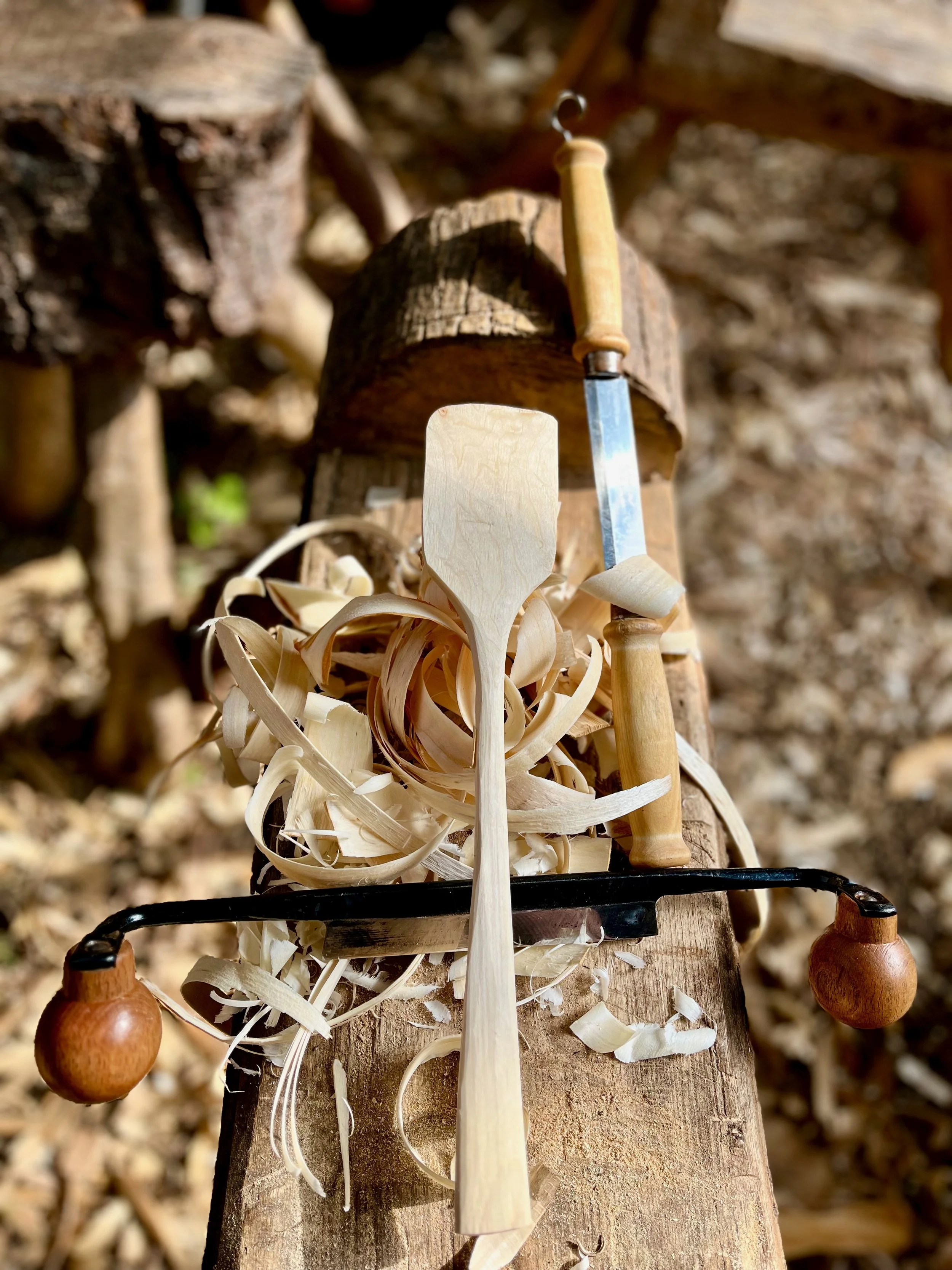 Woodworking tools and shavings on a wooden workbench in a woodworking shop.
