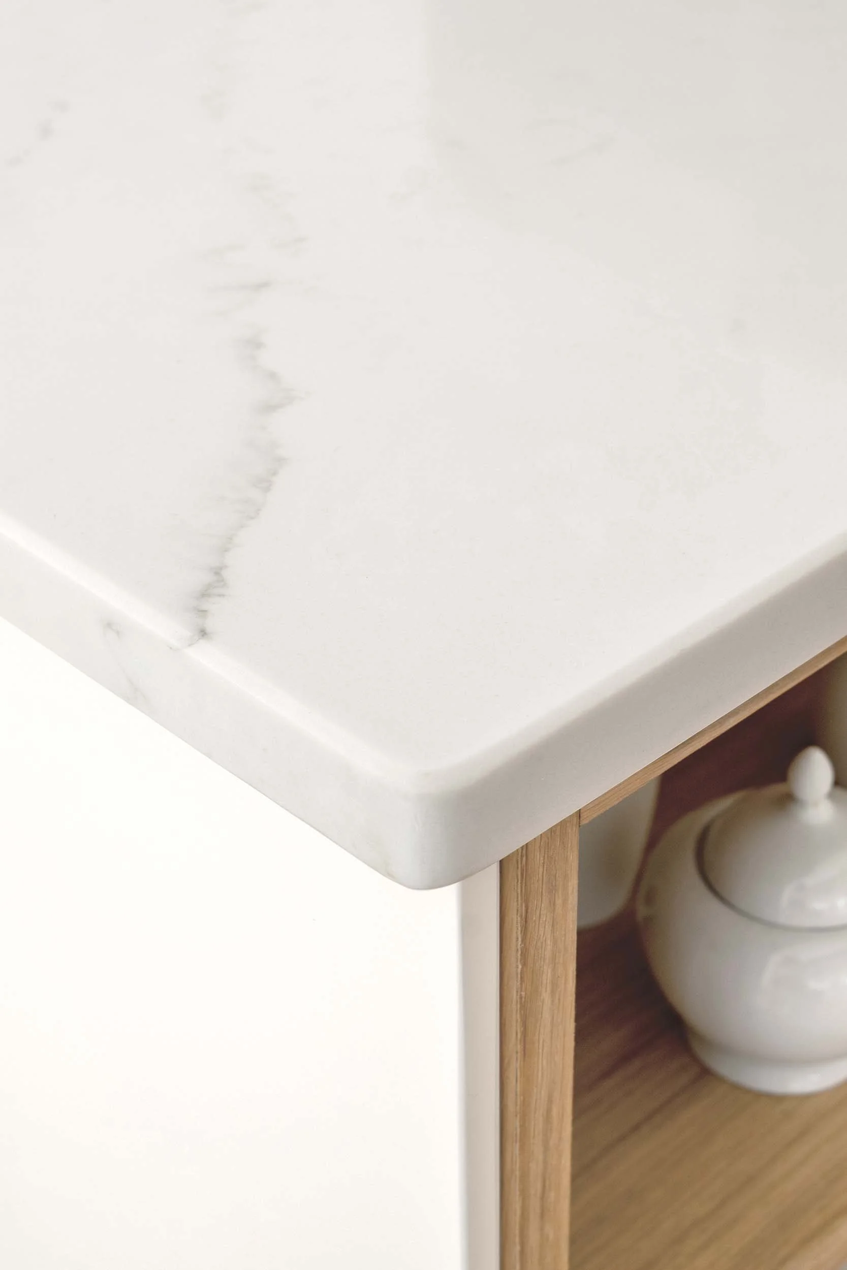 detailed shot of the corner of the marble worktop with off white side panel and timber shelving