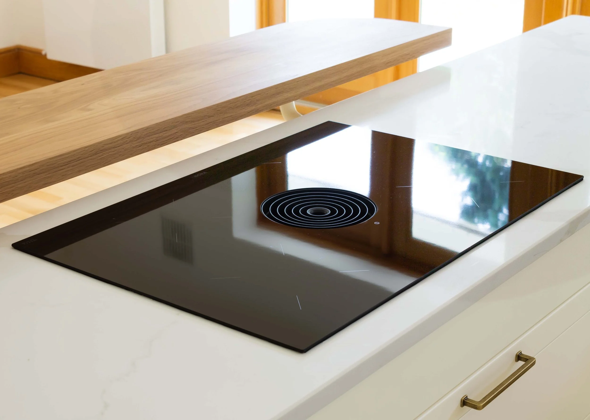 bora hob inset into marble worktop with timber breakfast bar and brass handles